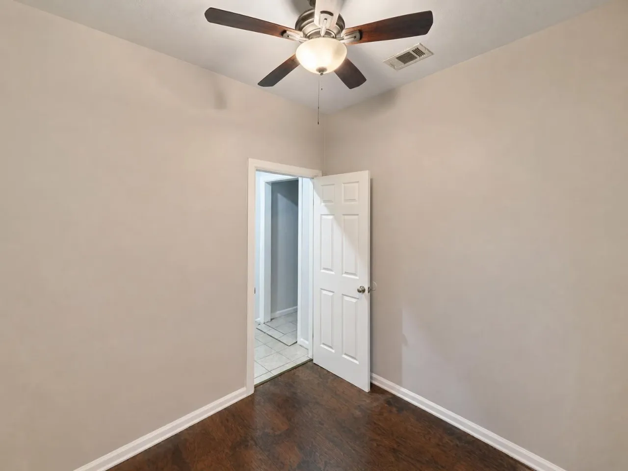 Wood-finish flooring, neutral wall color, ceiling fan with integrated lighting, and white trim