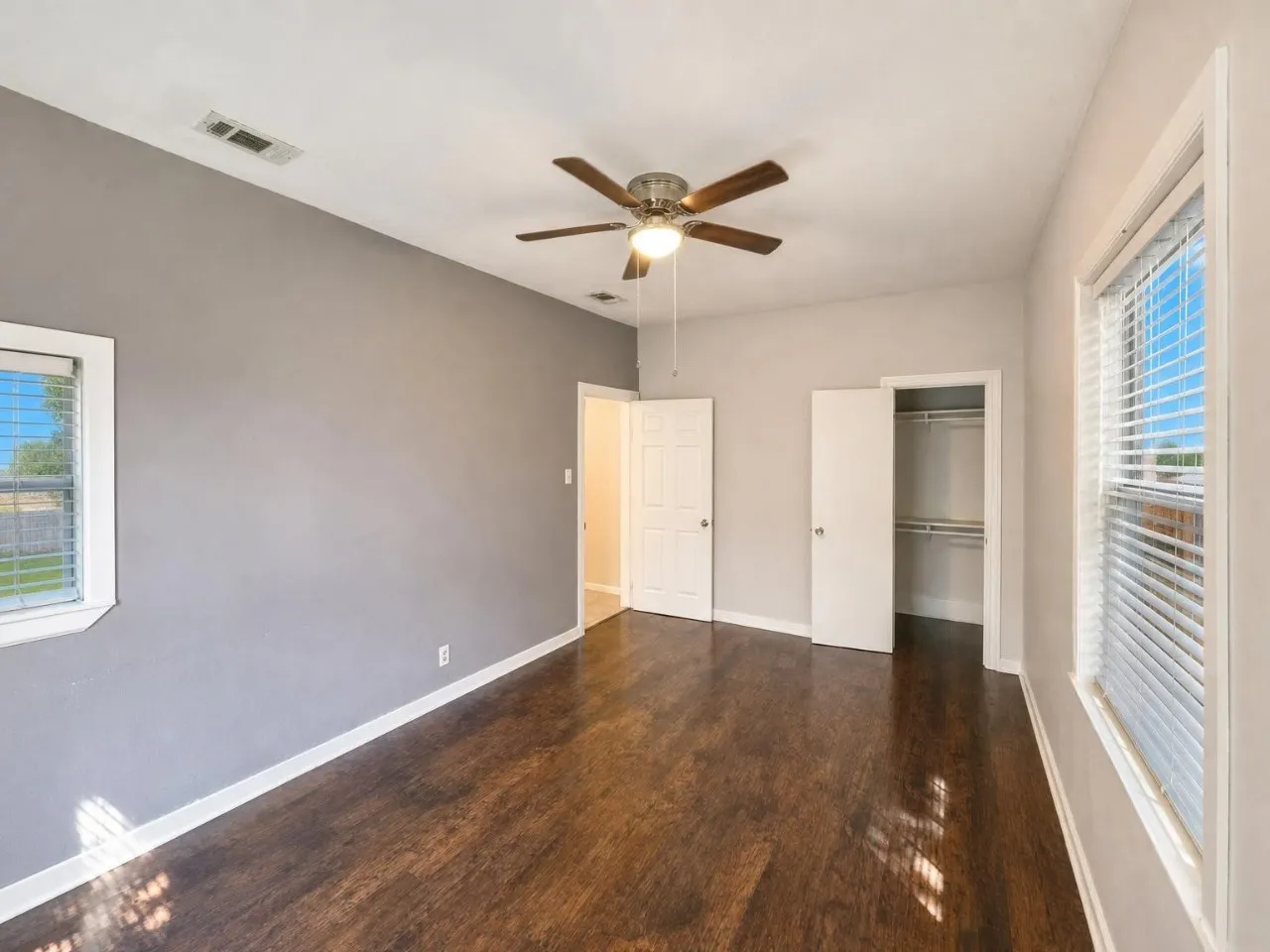 Hardwood flooring, ceiling fan, white trim, and a built-in closet with shelving
