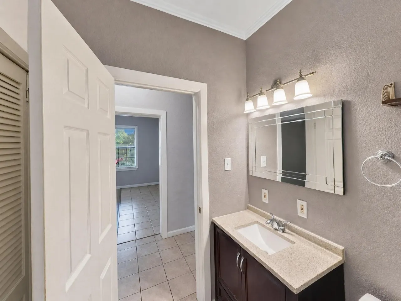 Vanity with integrated sink, wood-finish cabinetry, and stone-look countertop
