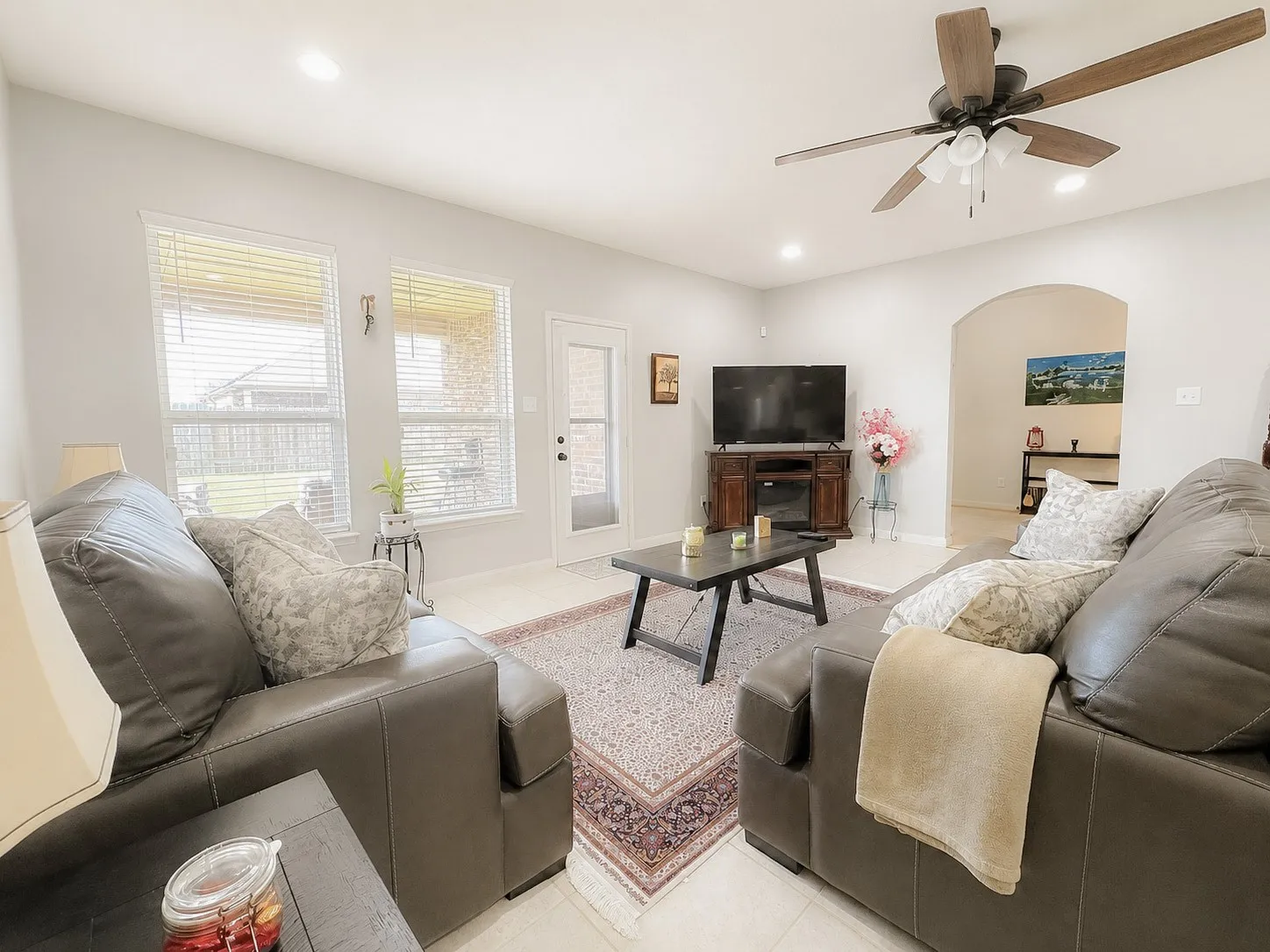 Recessed lighting throughout, arched doorway, ceiling fan with light fixture, tile flooring, and multiple windows