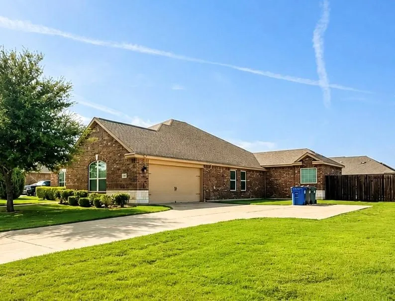 Brick exterior with stone accents, a gabled roof, an arched window, an attached garage, and a concrete driveway