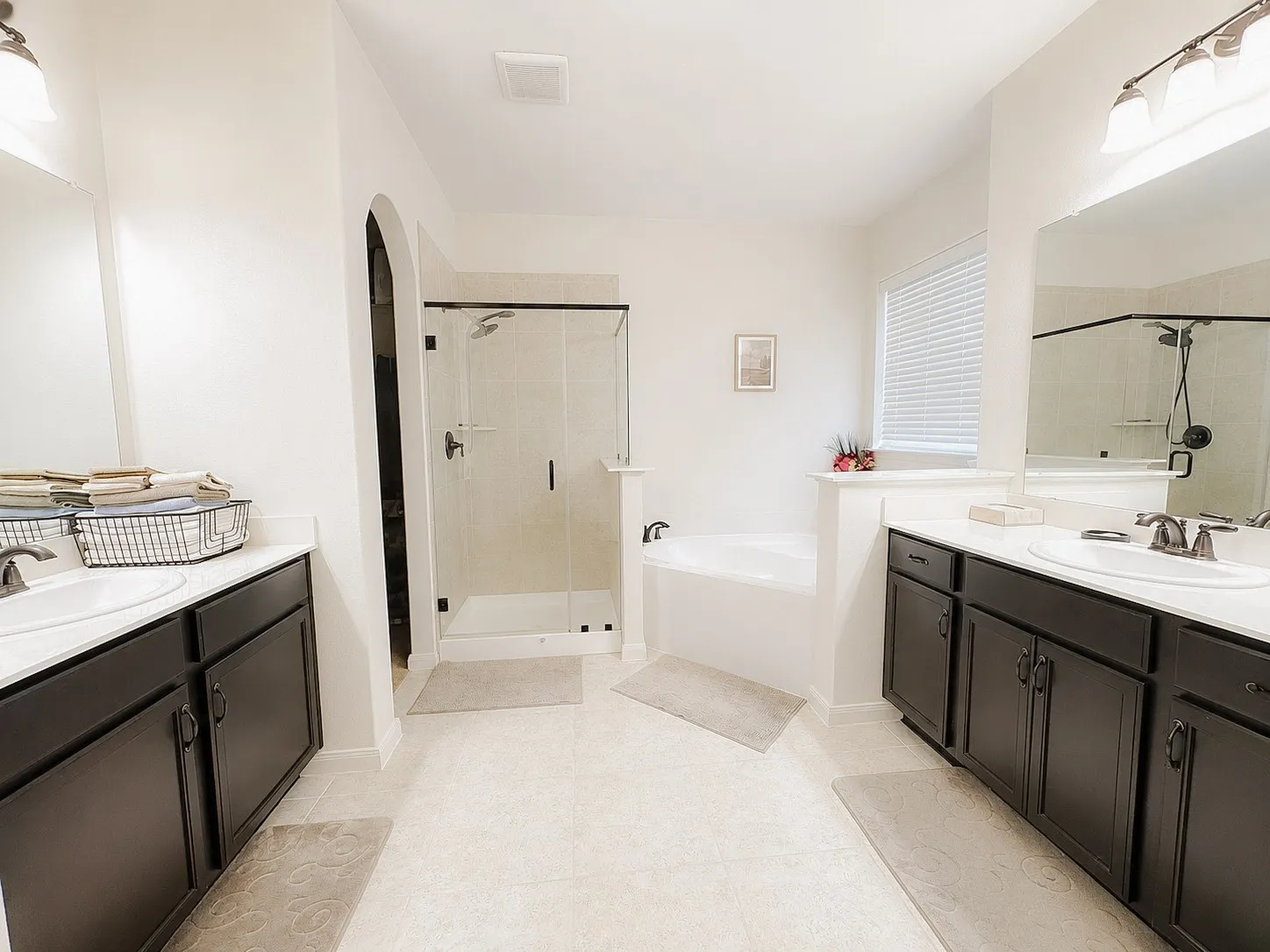 Dual vanities with undermount sinks, a freestanding soaking tub, and a glass-enclosed shower with tile surround