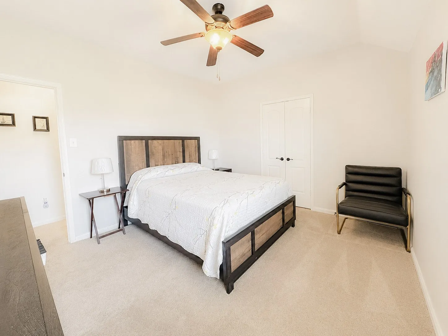 Neutral tone carpeting, vaulted ceiling, and a ceiling fan with light fixture