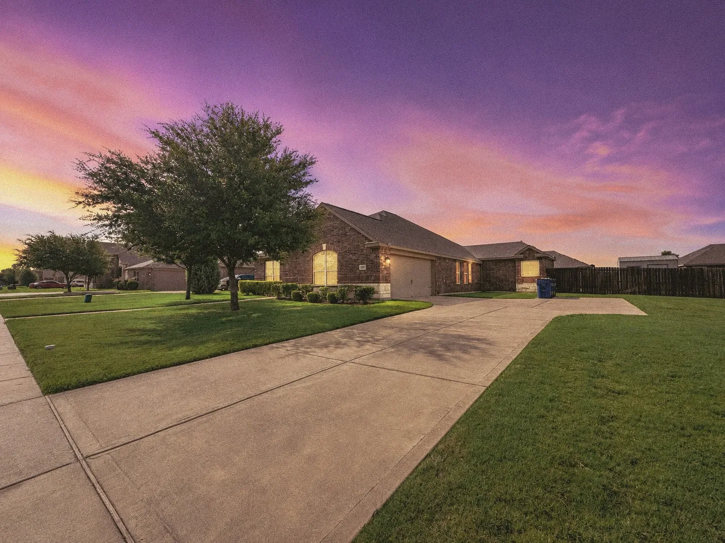 Brick exterior residence featuring a concrete driveway, attached garage, and a lush green lawn