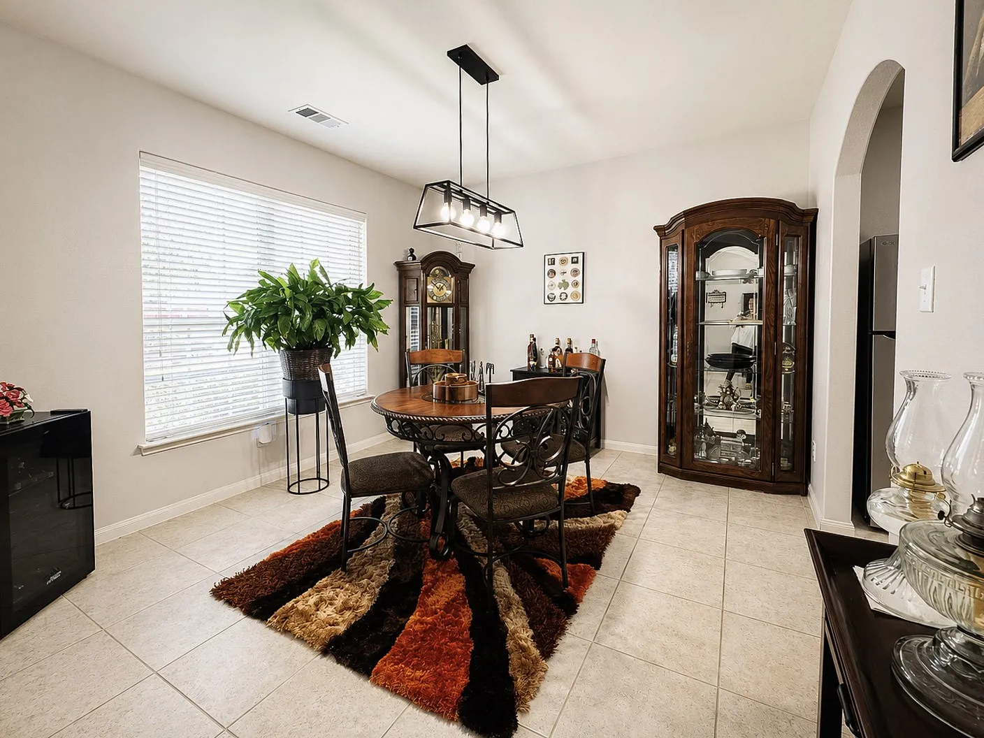 Recessed window with blinds, tiled flooring, arched doorway, and a contemporary linear chandelier