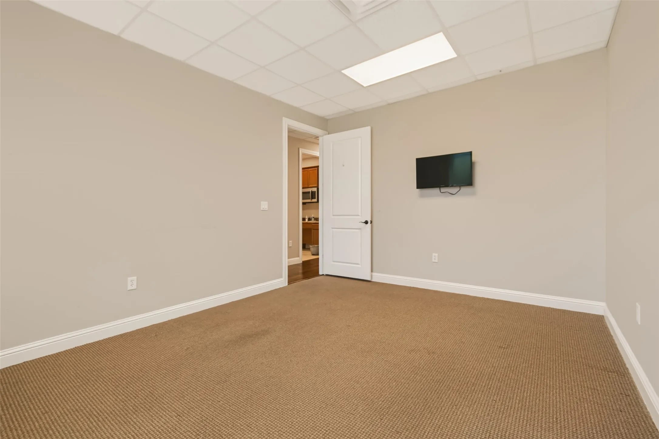 Neutral wall paint, drop ceiling with recessed lighting, and wall-to-wall carpeting