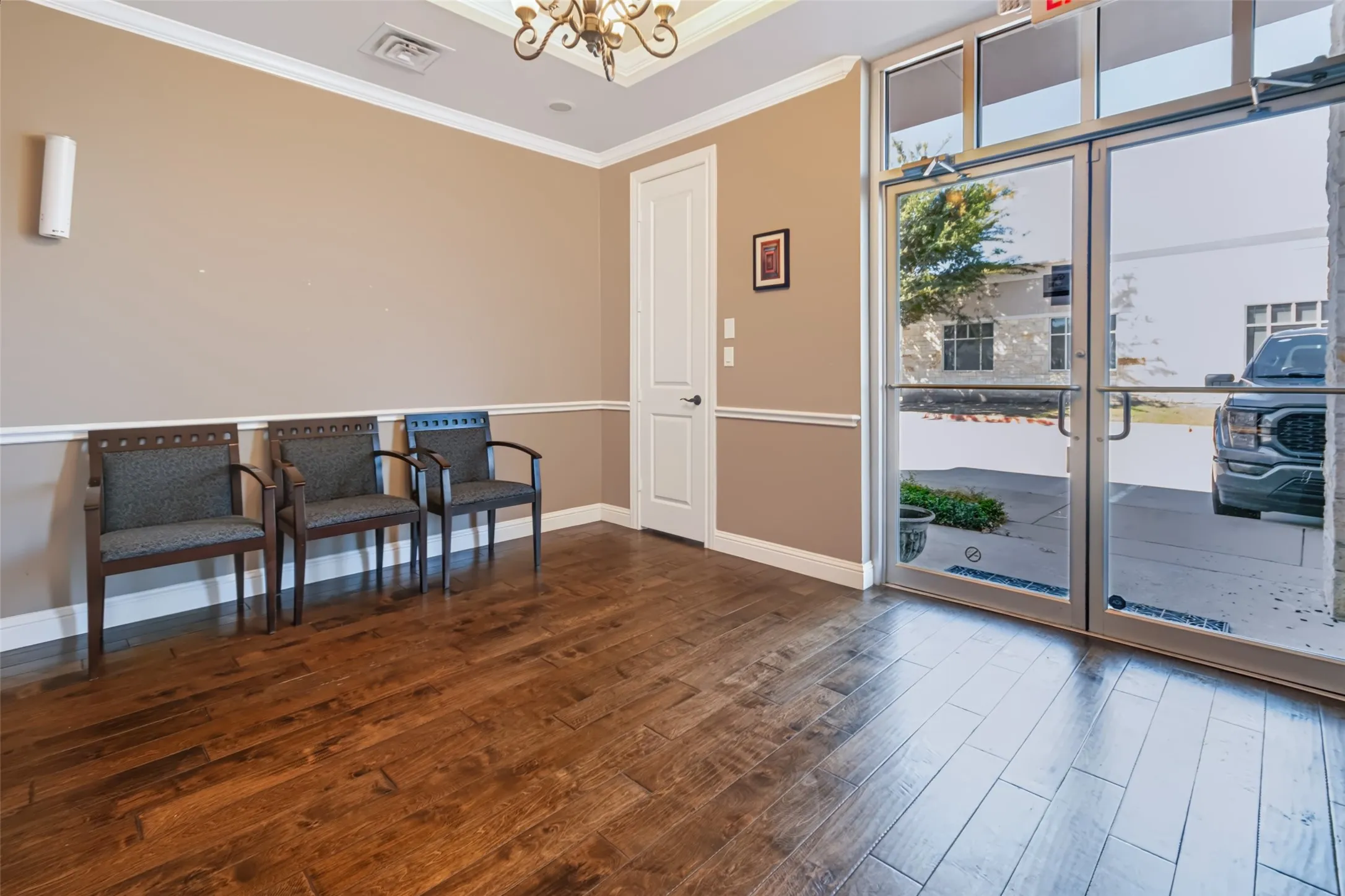 Wood-finish flooring, crown molding, chair rail, and a decorative ceiling fixture