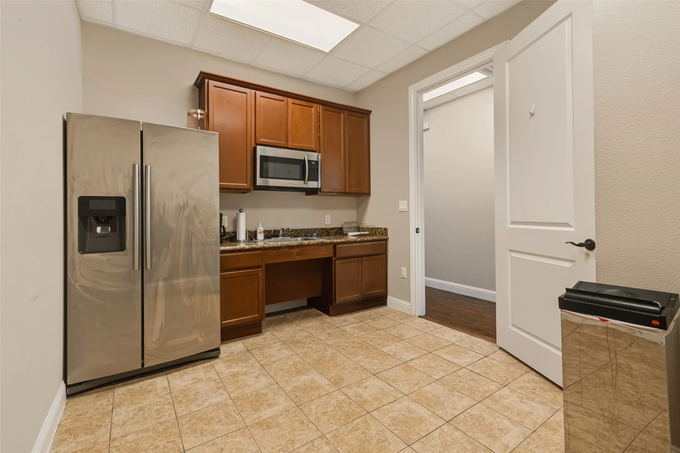 Built-in cabinetry with a microwave, stainless steel refrigerator, and tiled flooring