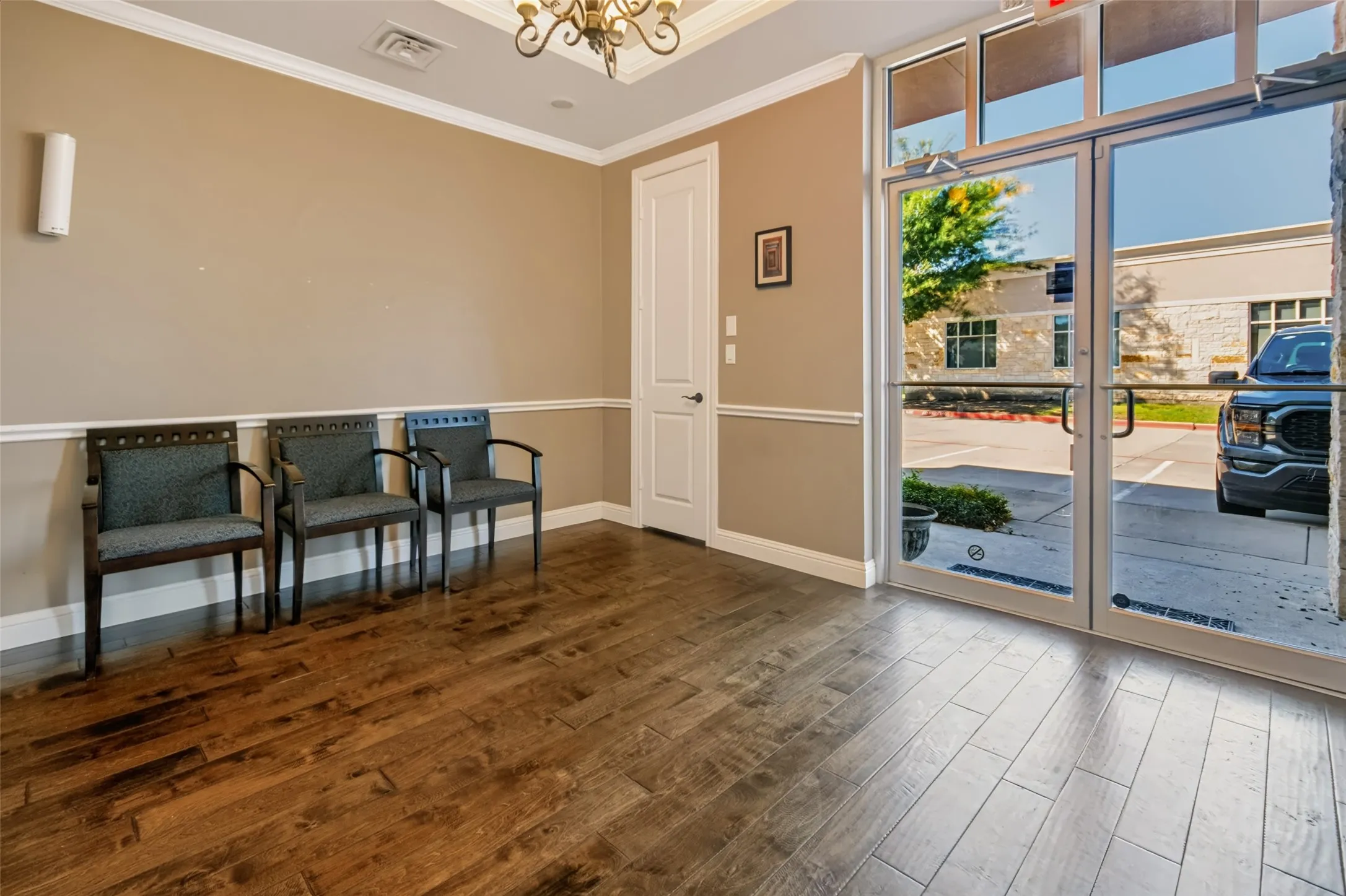Wood-finish flooring, crown molding, chair rail molding, and a chandelier with decorative ceiling medallion