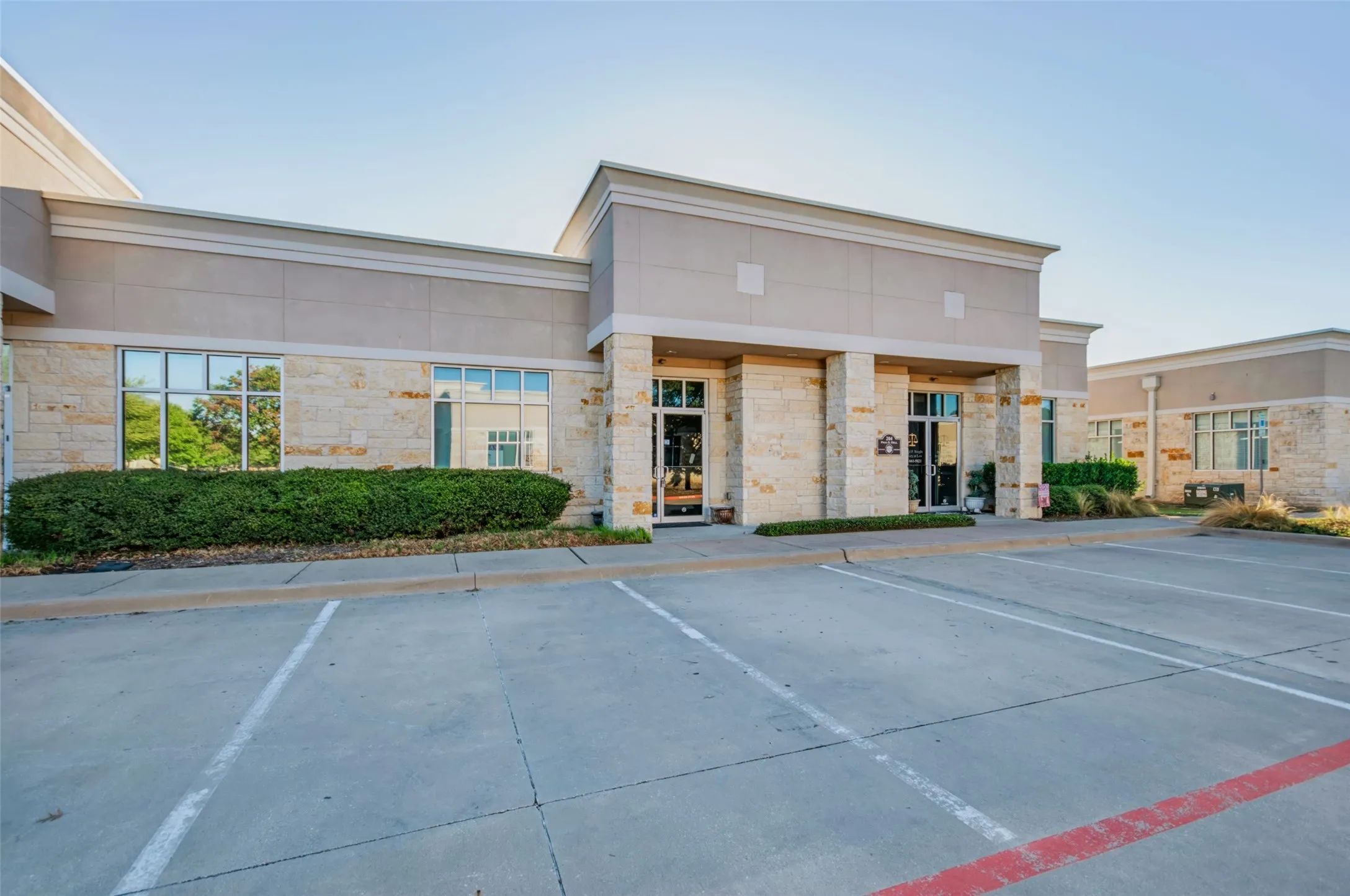 Stone and stucco exterior with multiple large windows, a prominent covered entrance, and a dedicated paved parking area