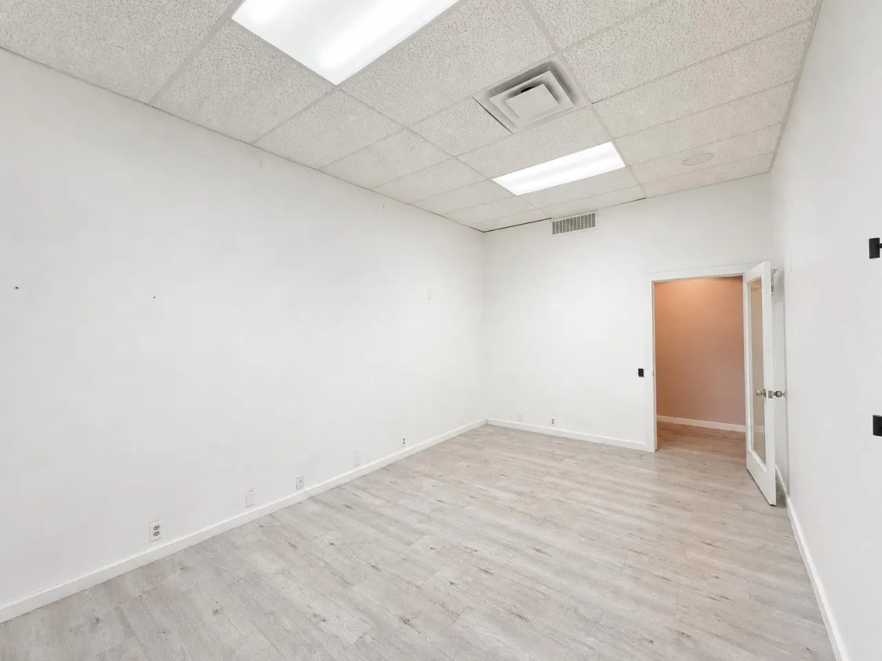 Wood-finish flooring, white walls, drop ceiling, recessed lighting, and glass-paneled interior door