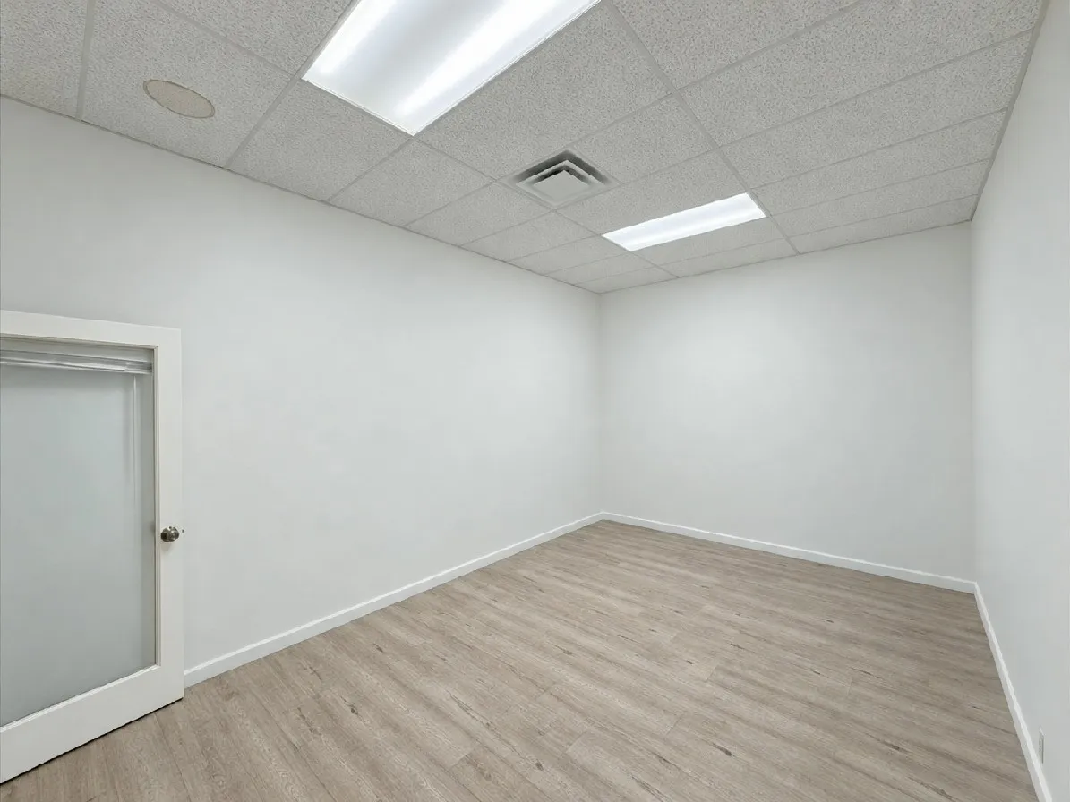 Wood-finish flooring, white walls, and a suspended ceiling with recessed lighting and a ventilation register