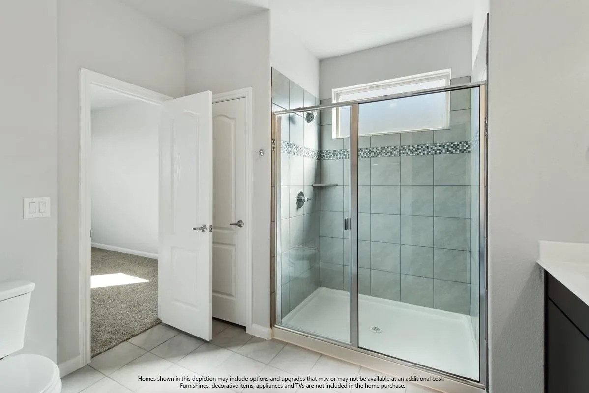 Glass-enclosed shower with subway tile surround, accent tile band, and built-in shelf
