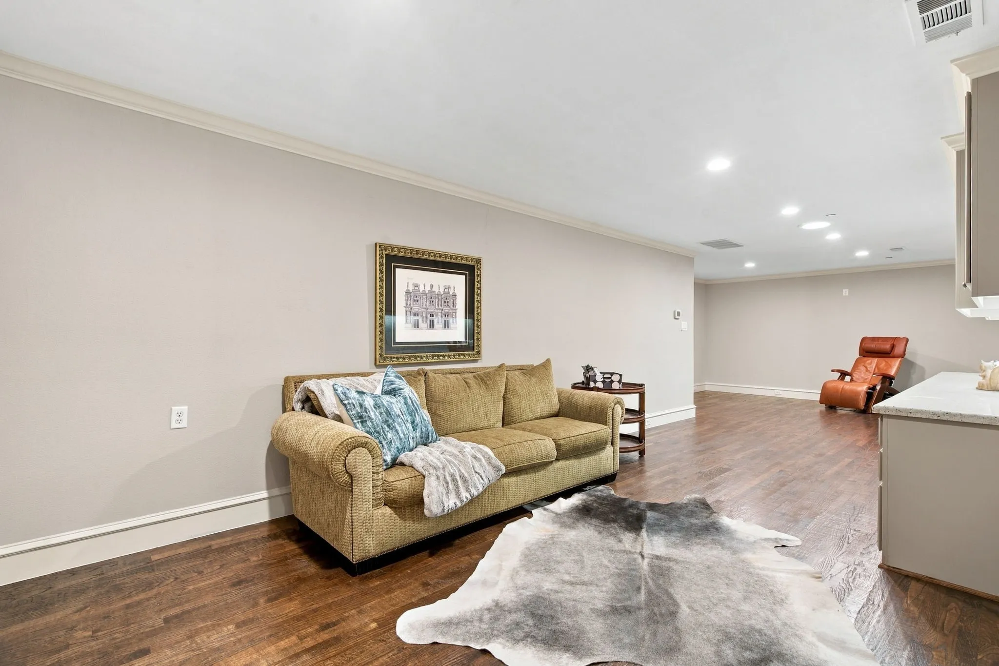 Spacious room featuring wood-finish flooring, recessed lighting, crown molding, and a built-in cabinet with a light-toned countertop