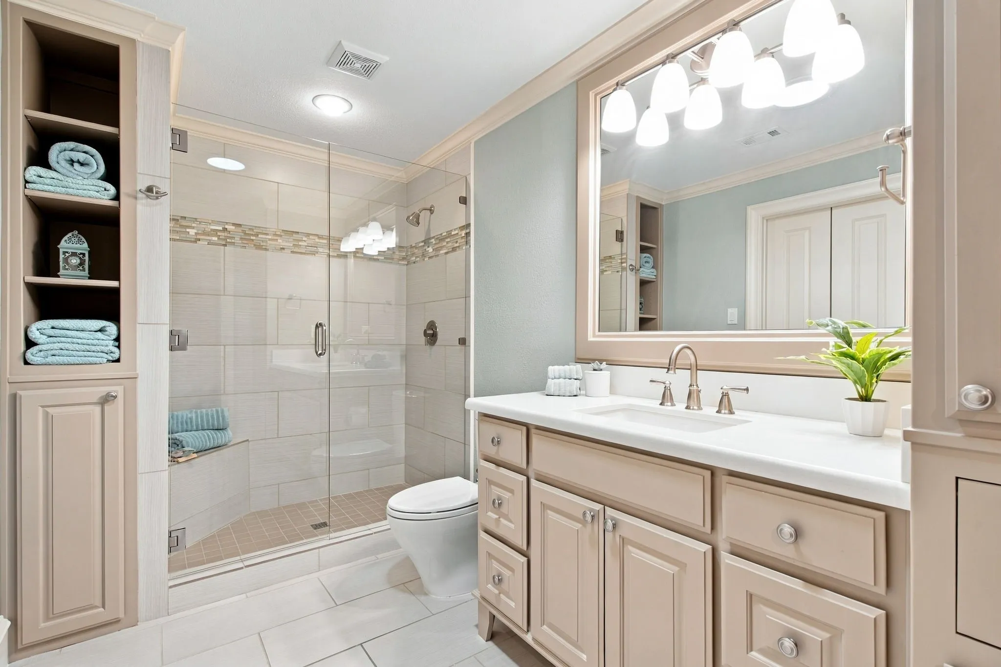 Glass-enclosed shower with a built-in bench and decorative tile accent