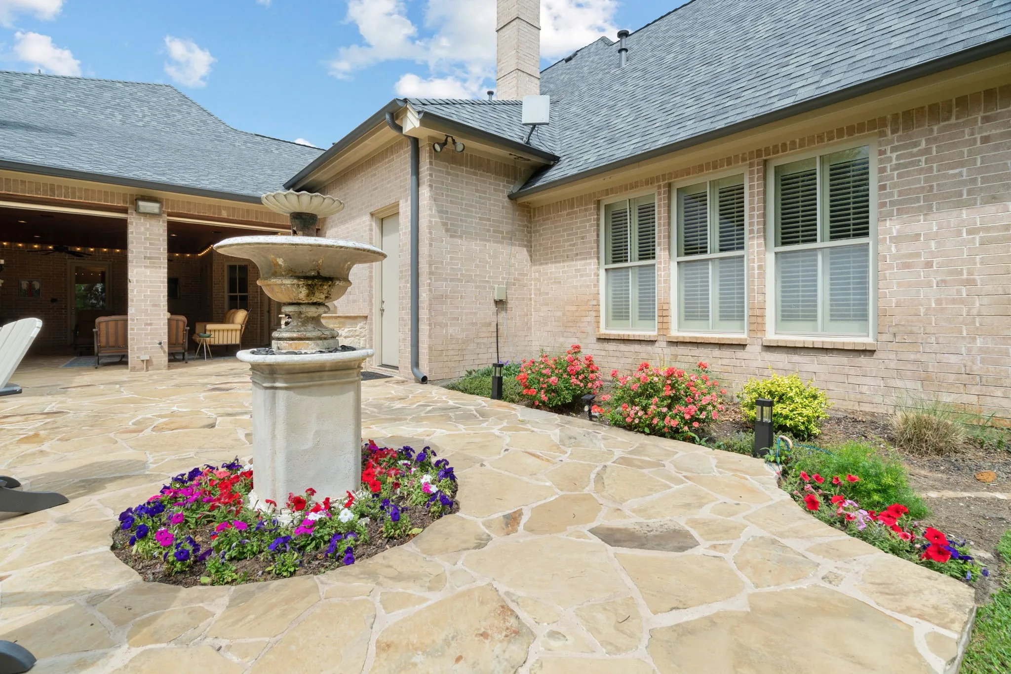 Flagstone patio with a multi-tiered fountain and surrounding floral beds
