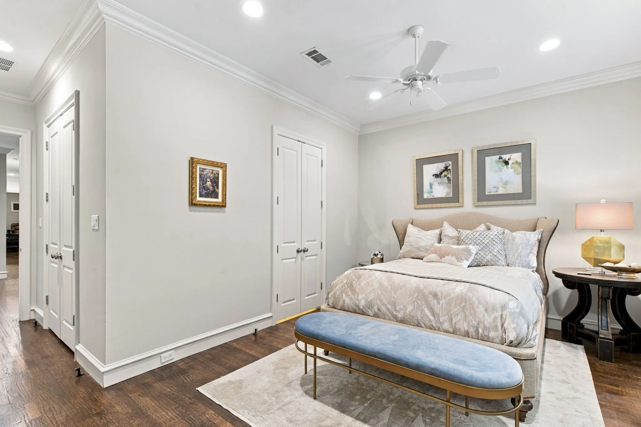 Wood-finish flooring, crown molding, ceiling fan with integrated lighting, recessed lighting, and white bi-fold closet doors