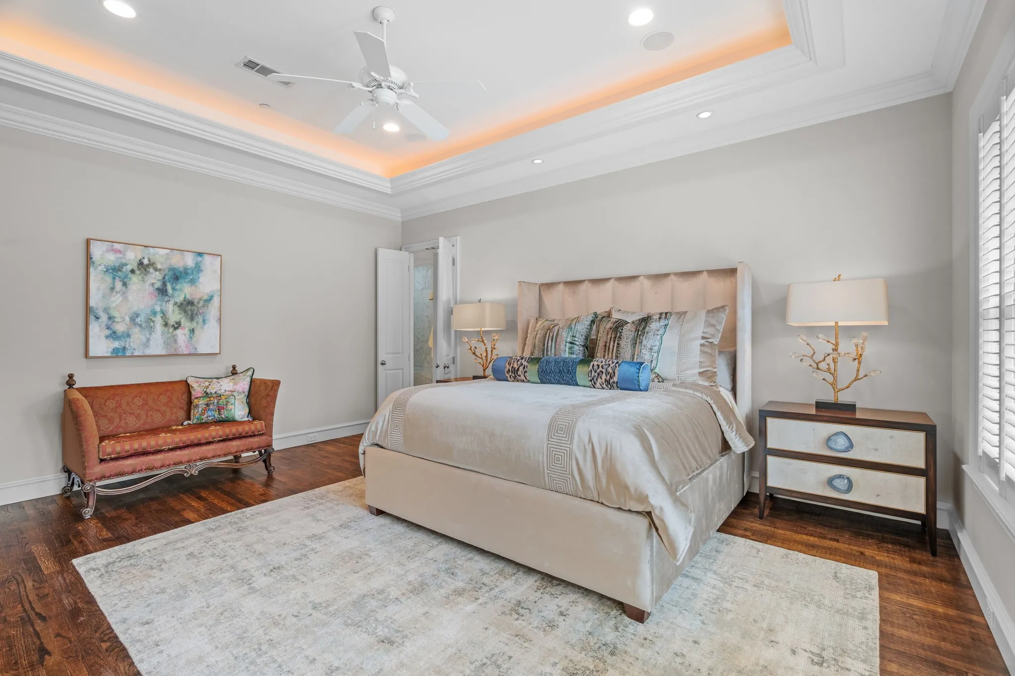 Tray ceiling with cove lighting and recessed fixtures, crown molding, dark wood-finish flooring, and plantation shutters