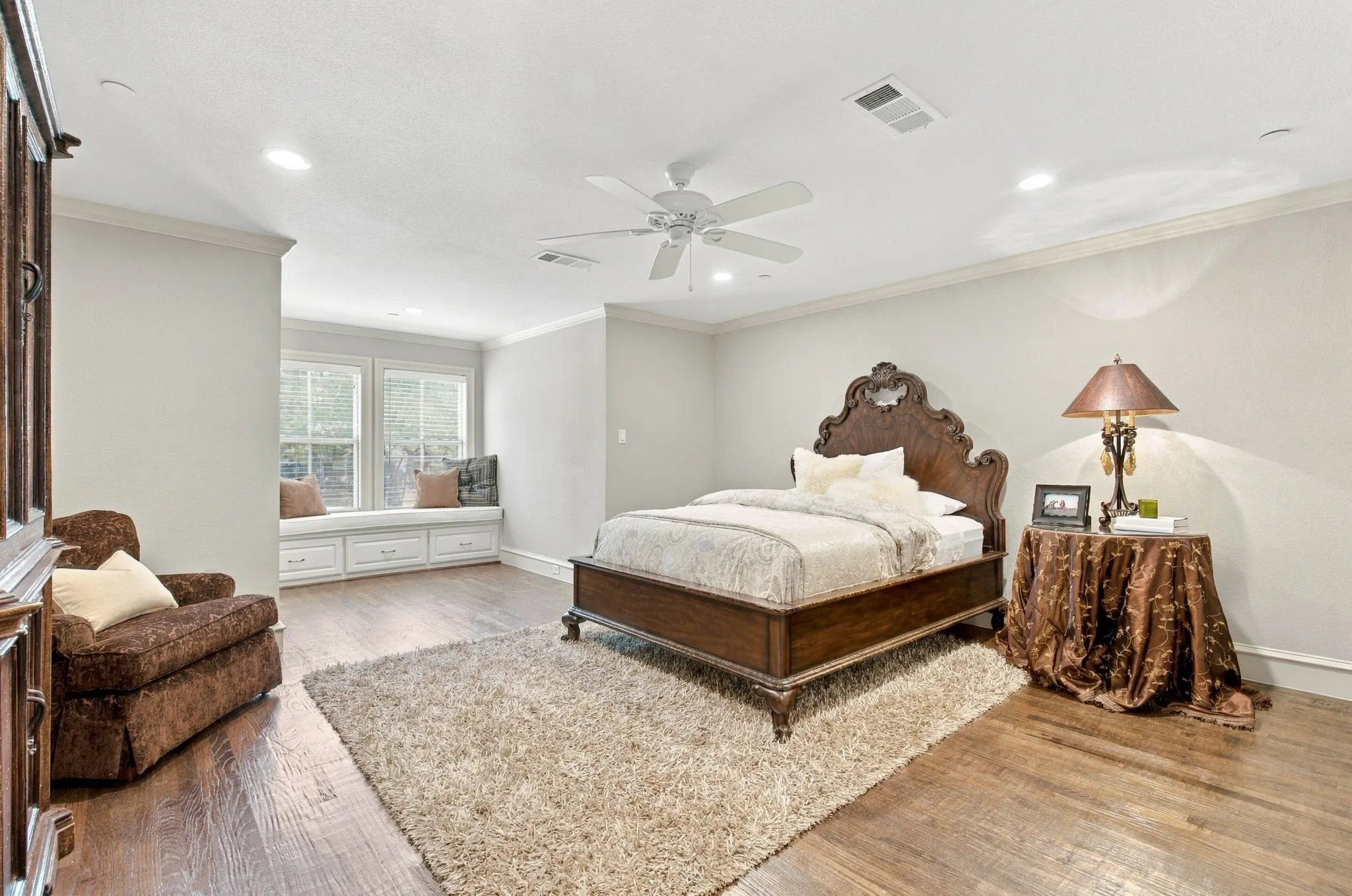 Wood-finish flooring, recessed lighting, crown molding, ceiling fan, and a built-in window bench with storage