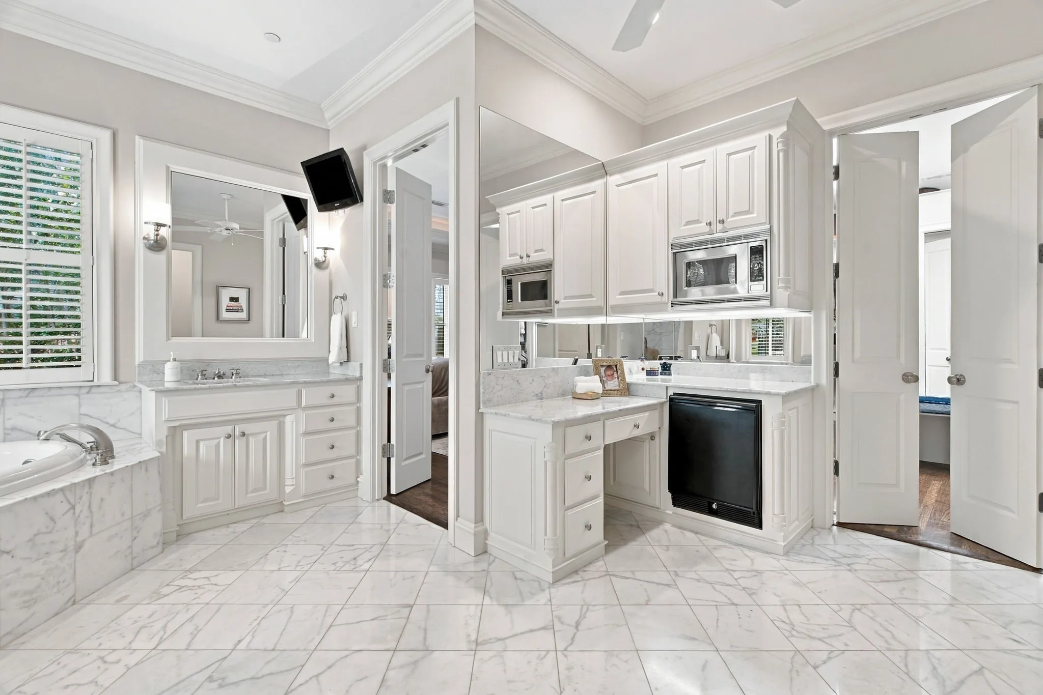 Marble tile flooring, built-in cabinetry, dual vanities with stone countertops, and a built-in jetted tub