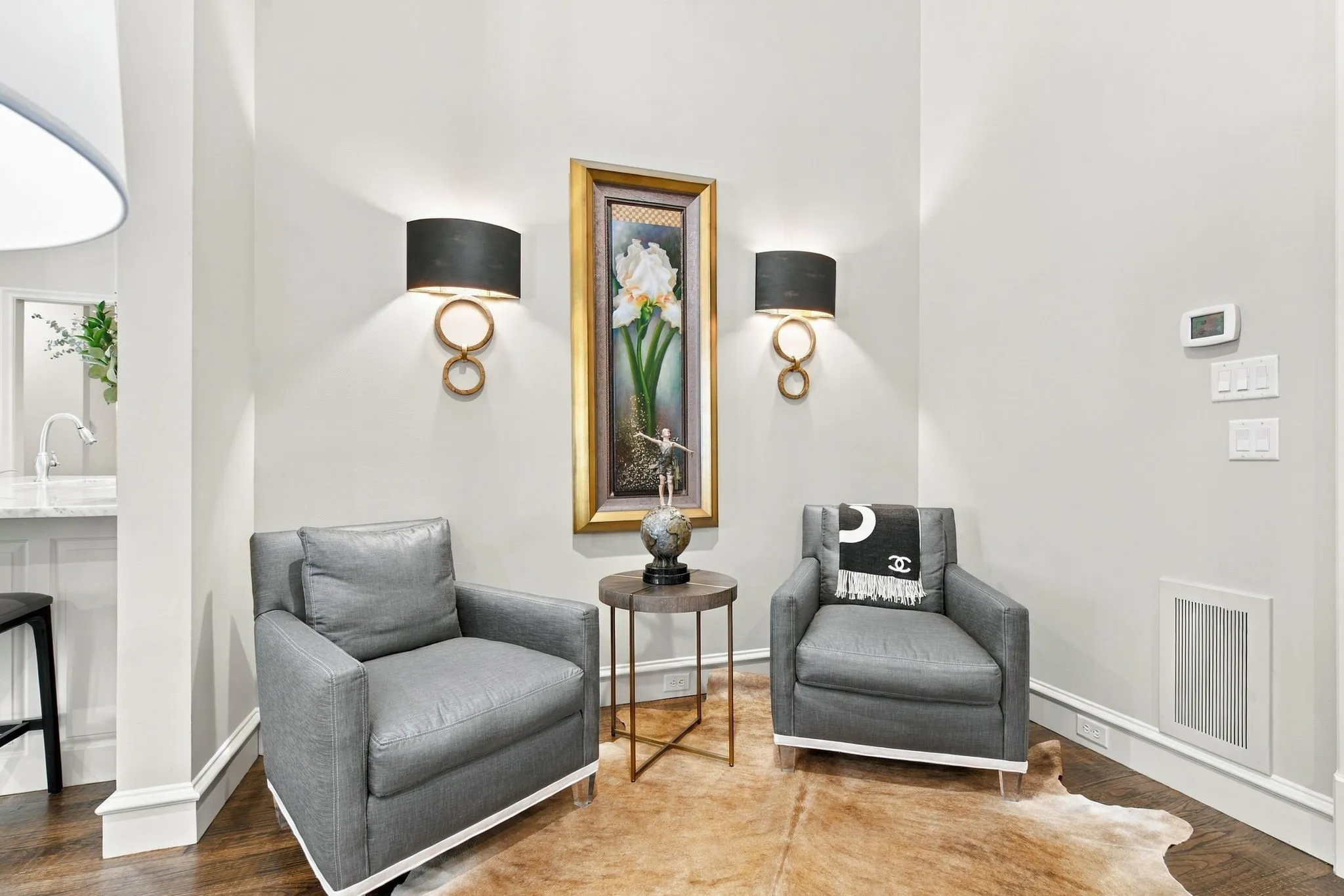Hardwood flooring, decorative wall sconces, white wall paneling, and a marble countertop