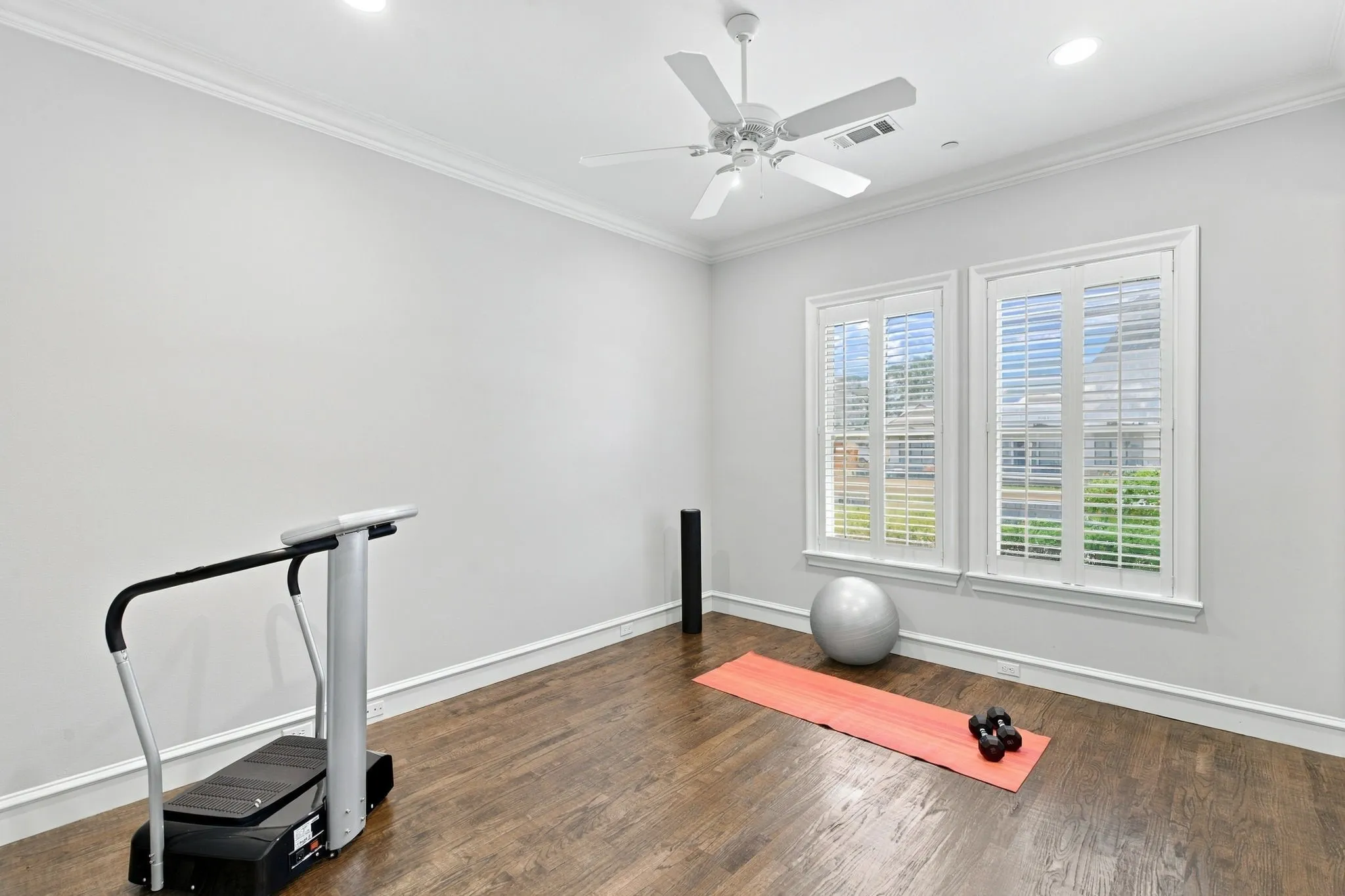 Hardwood-style flooring, dual windows with plantation shutters, recessed lighting, crown molding, and a ceiling fan