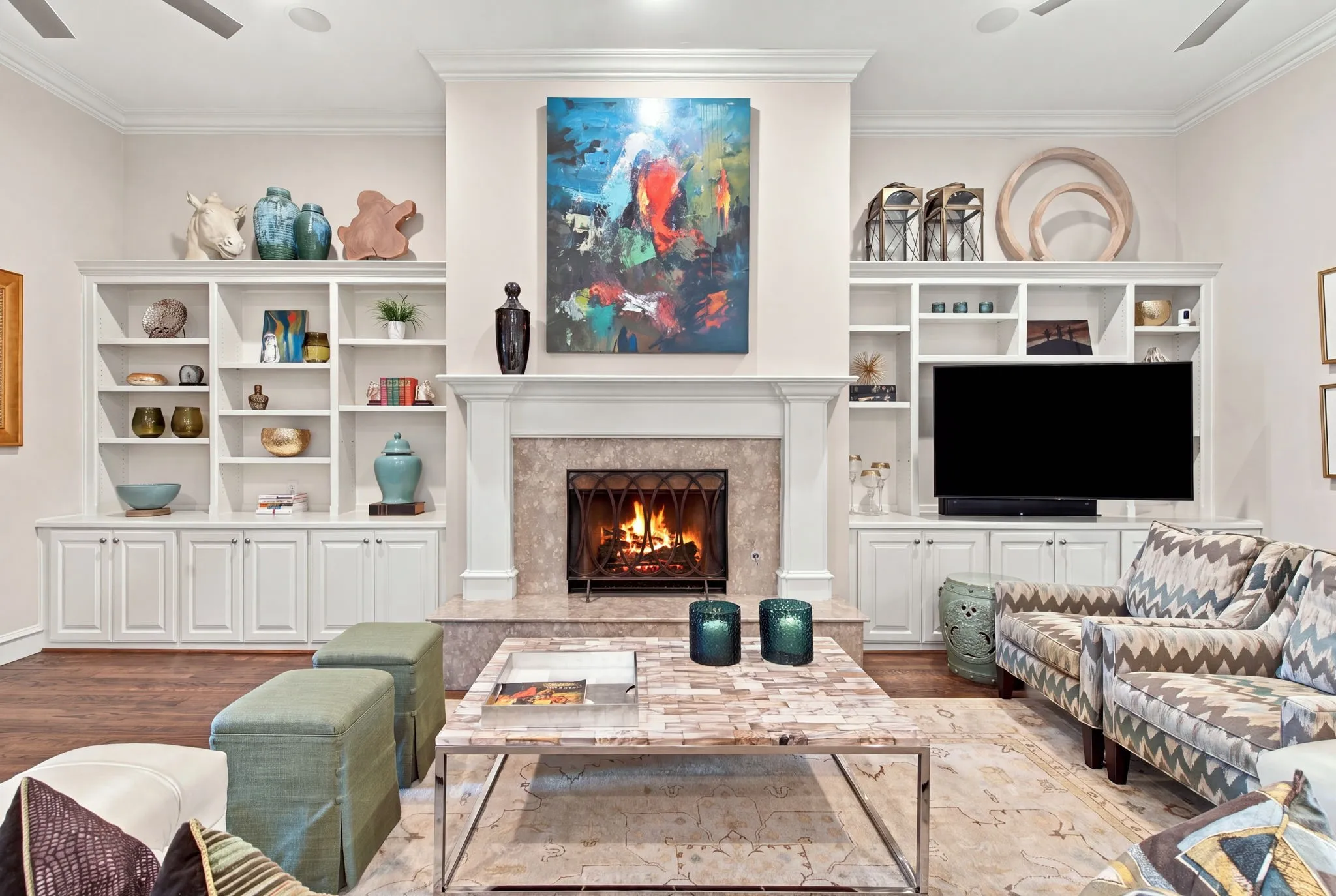 Built-in shelving with lower cabinetry, central fireplace with a stone surround, recessed lighting, and wood-finish flooring