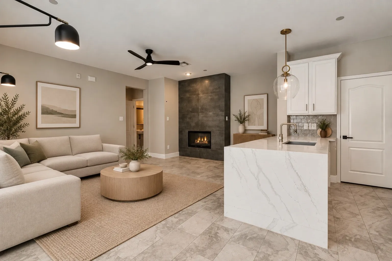 Integrated living space featuring a tiled fireplace with a built-in firebox, a kitchen island with a waterfall countertop, white cabinetry with a subway tile backsplash, and overhead lighting fixtures