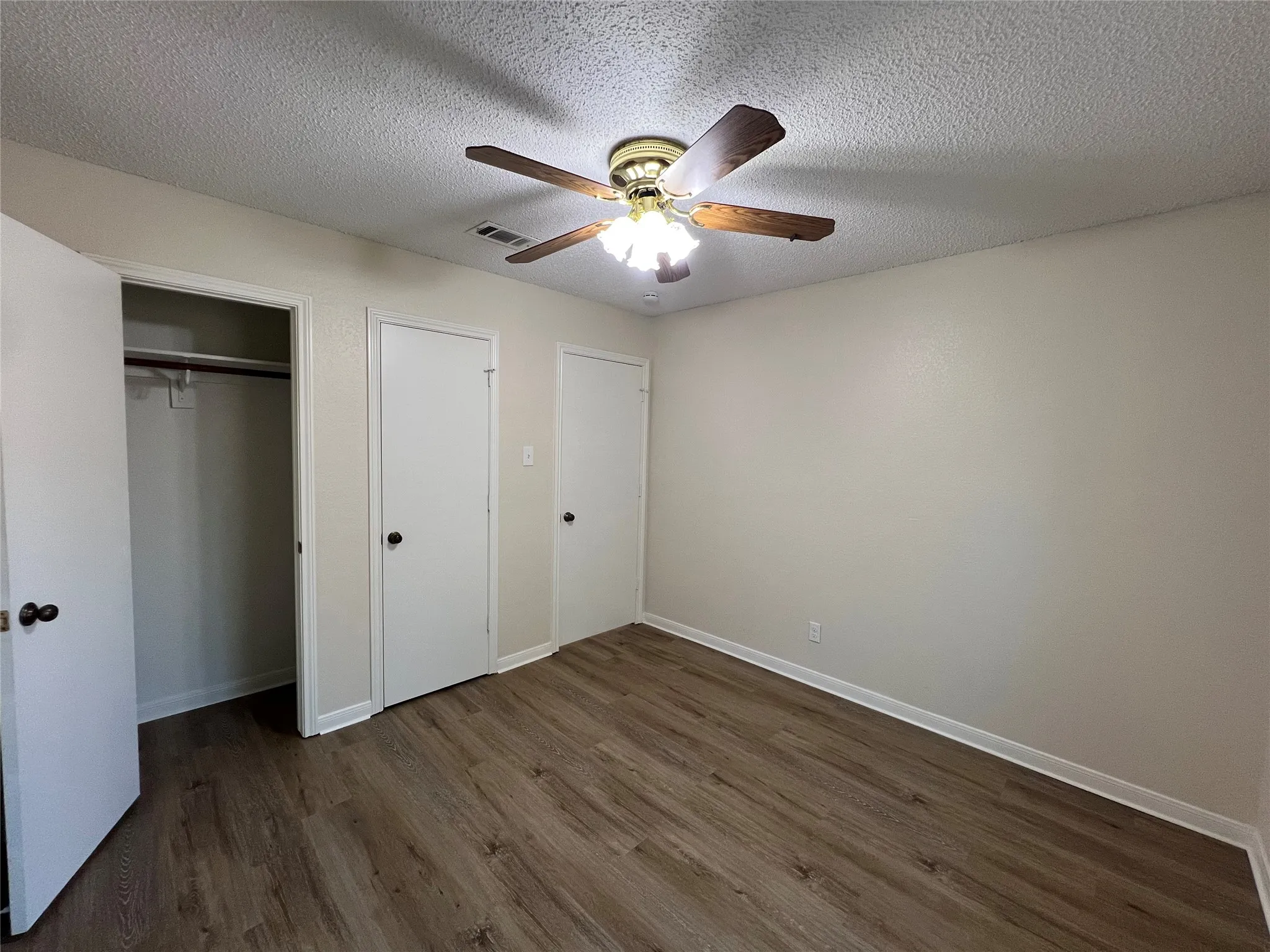 Wood-finish flooring, ceiling fan with integrated lighting, neutral wall paint, and white trim