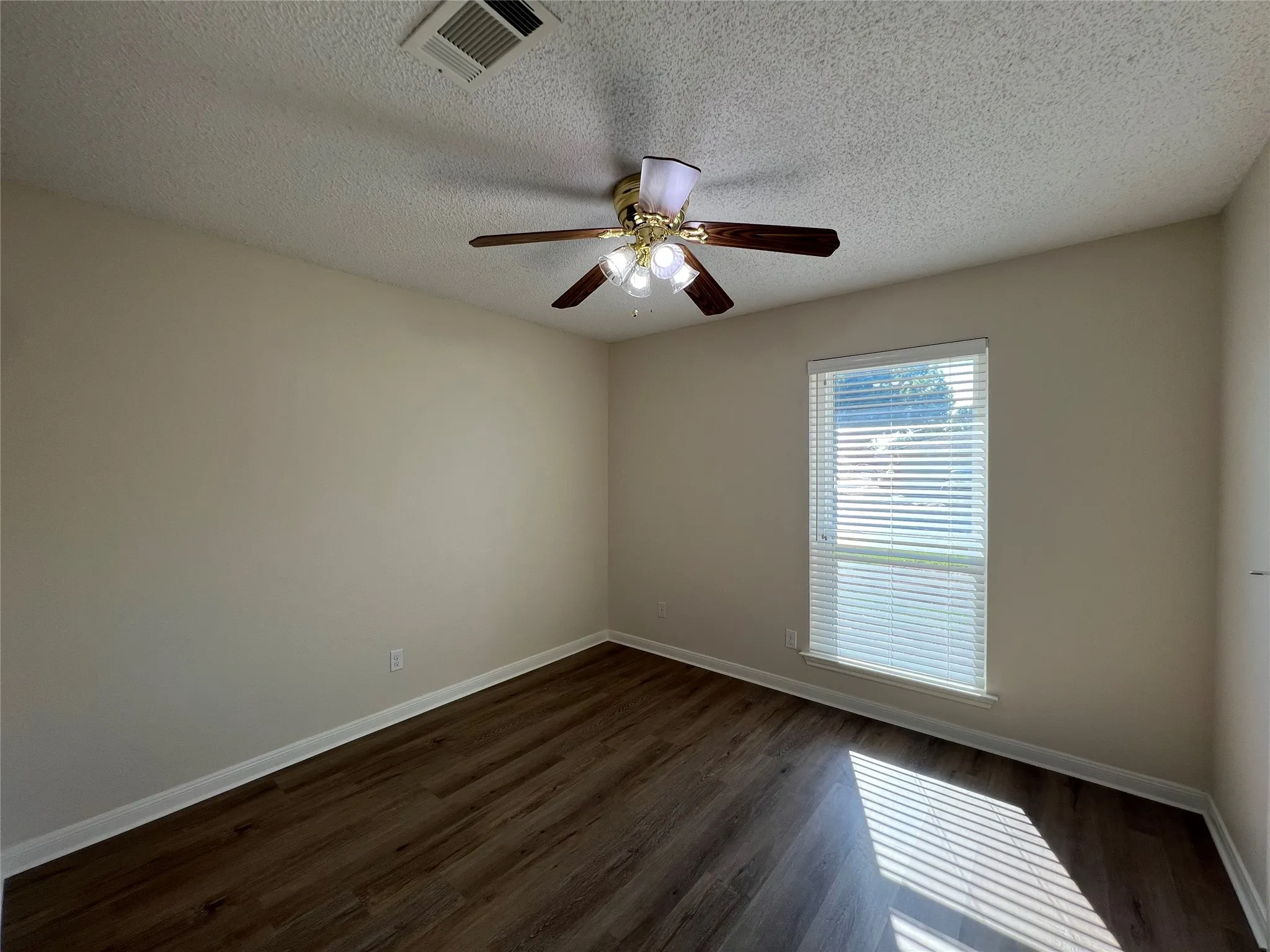 Wood-finish flooring, single window with blinds, ceiling fan with integrated lighting, and neutral wall paint