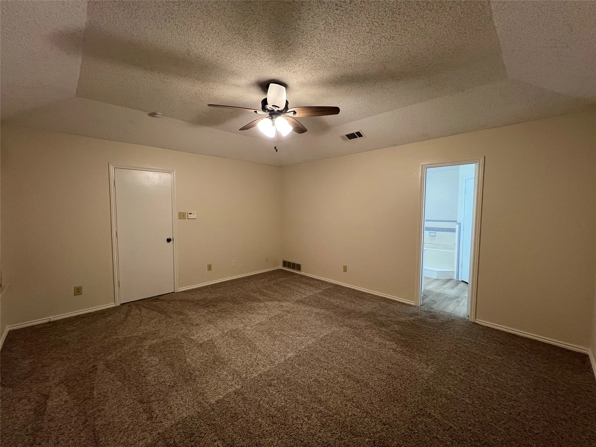 Carpeted flooring, ceiling fan with light fixture, recessed ceiling detail, and neutral wall tones