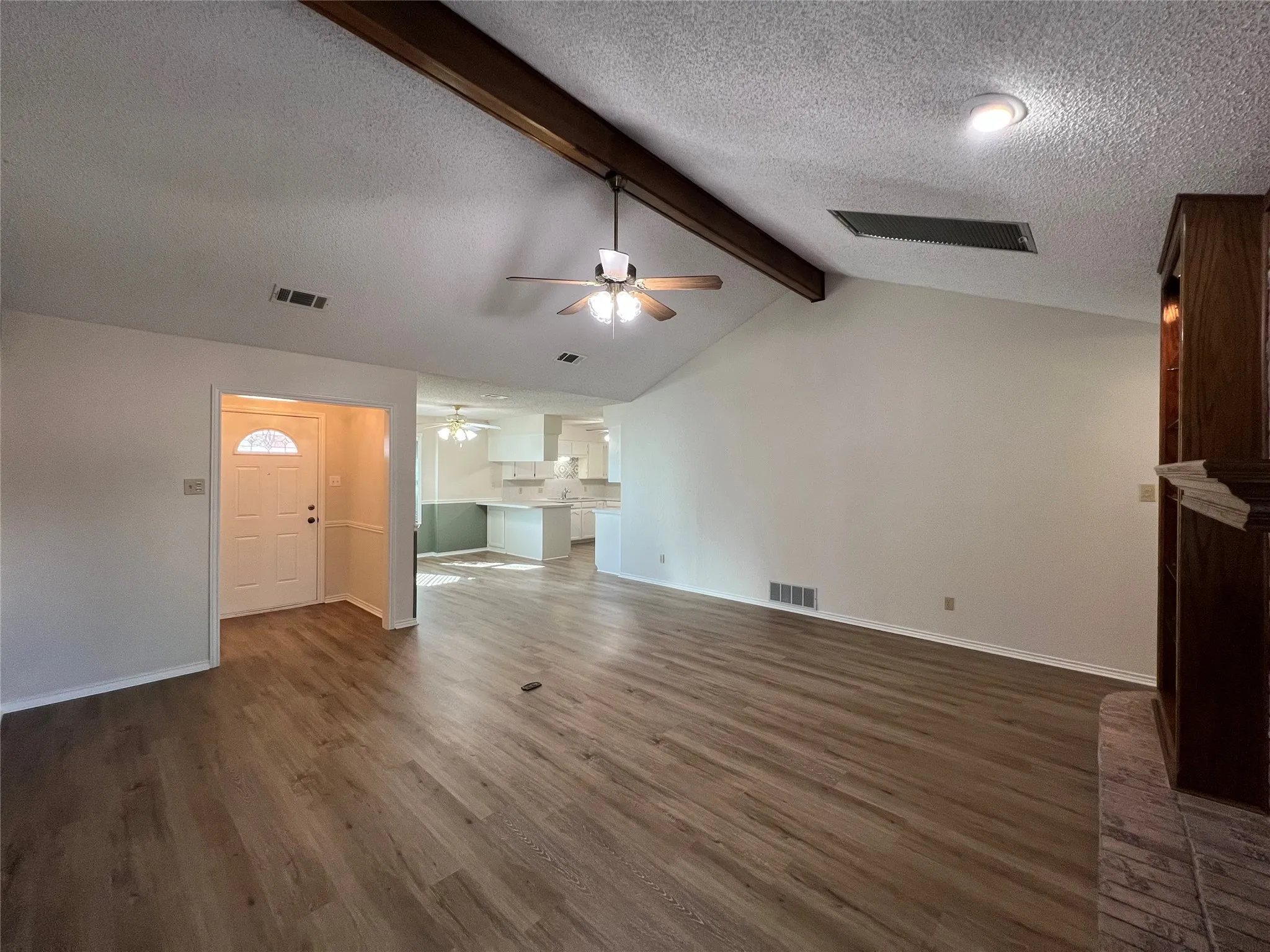 Vaulted ceiling with exposed wood beam, wood-finish flooring, recessed lighting, and a ceiling fan