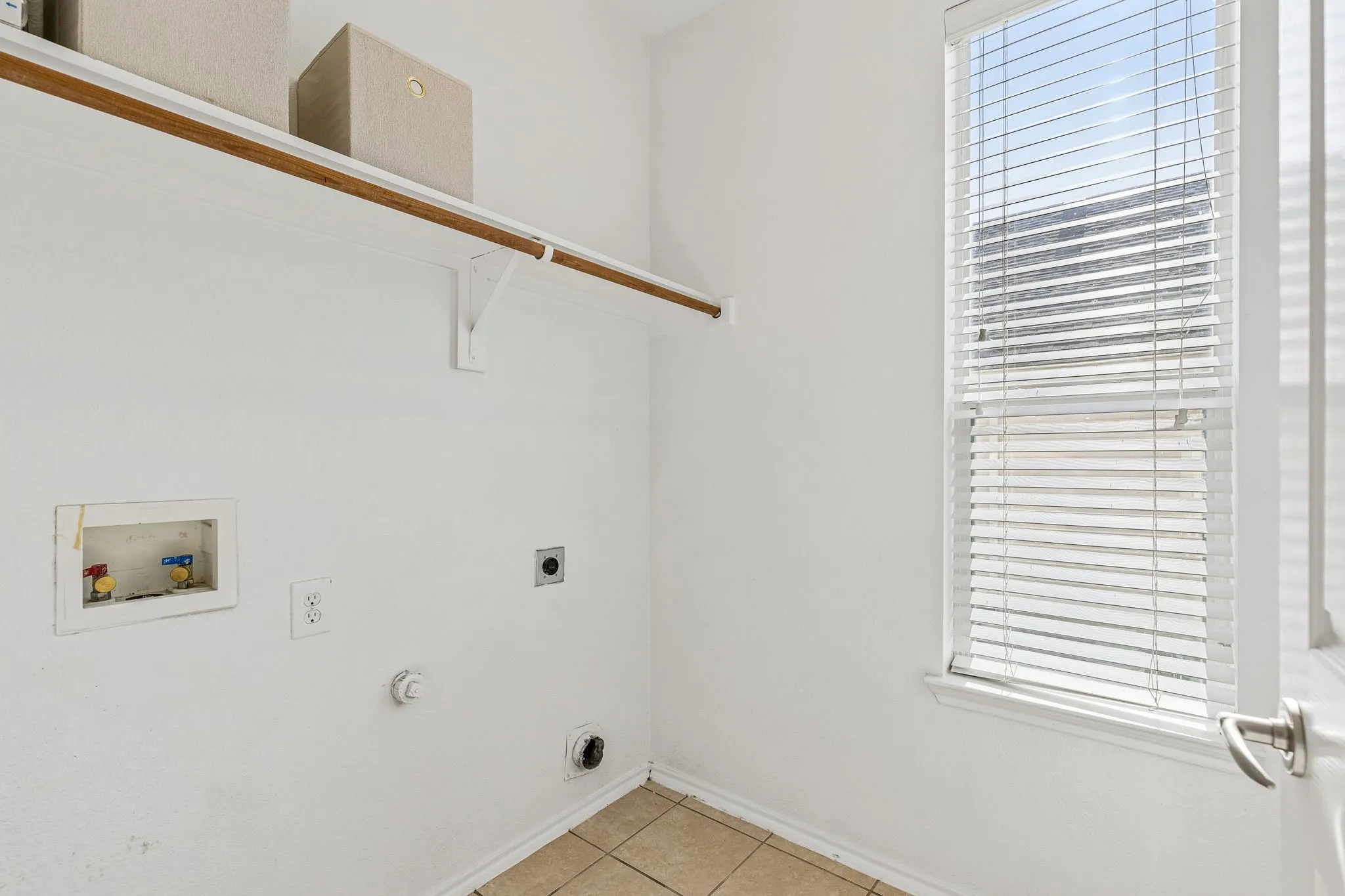 The spacious utility room includes built-in shelving to keep laundry and household essentials neatly organized.