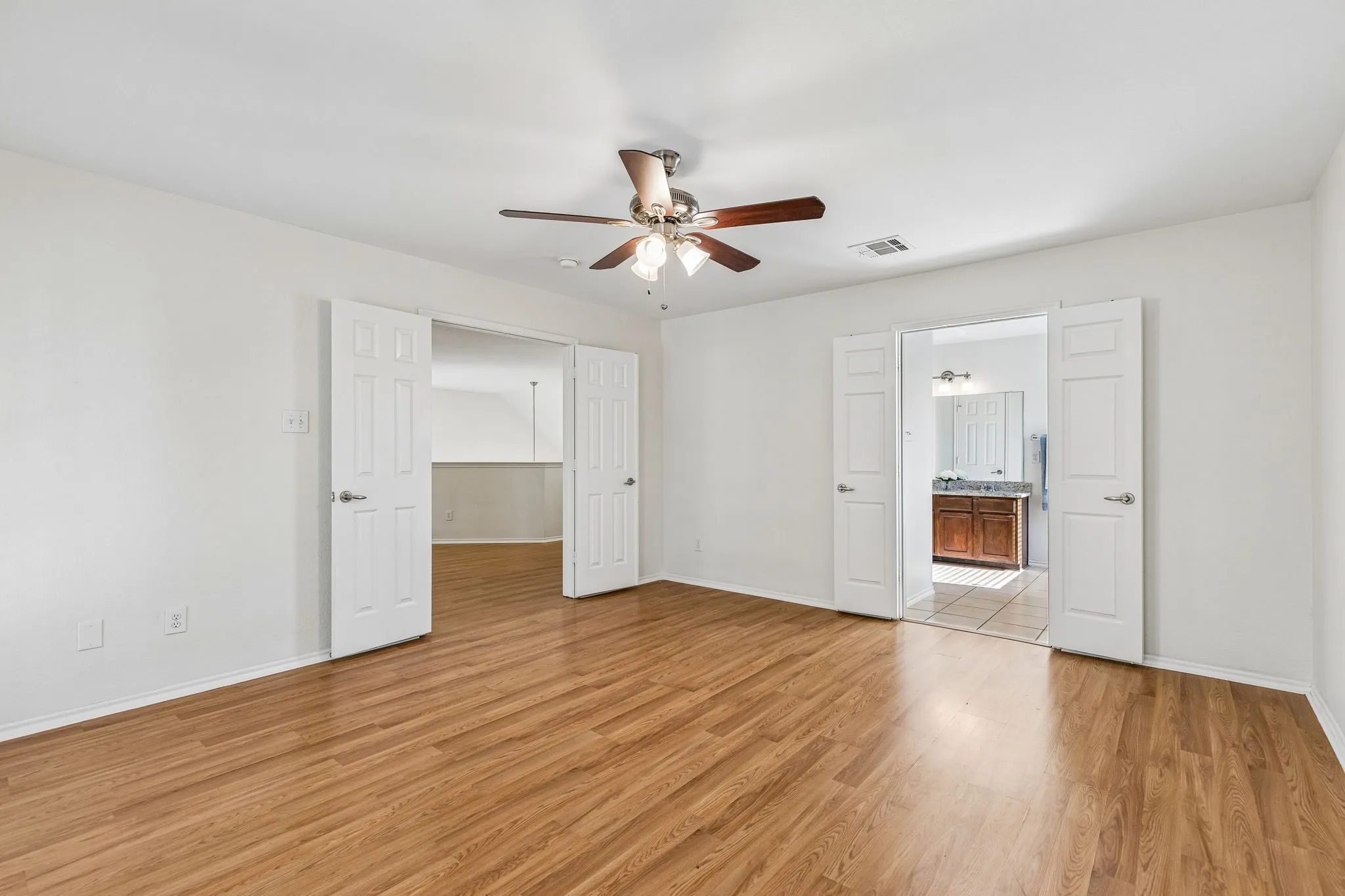 Large windows fill the primary suite with natural light while providing direct access to the covered balcony.