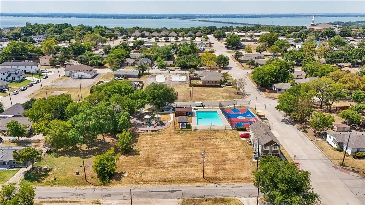 Expansive property featuring a swimming pool, paved court, and surrounding natural landscaping