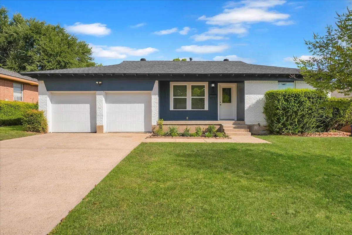 Exterior featuring a two-car garage, white brick facade, dark siding, and a concrete driveway