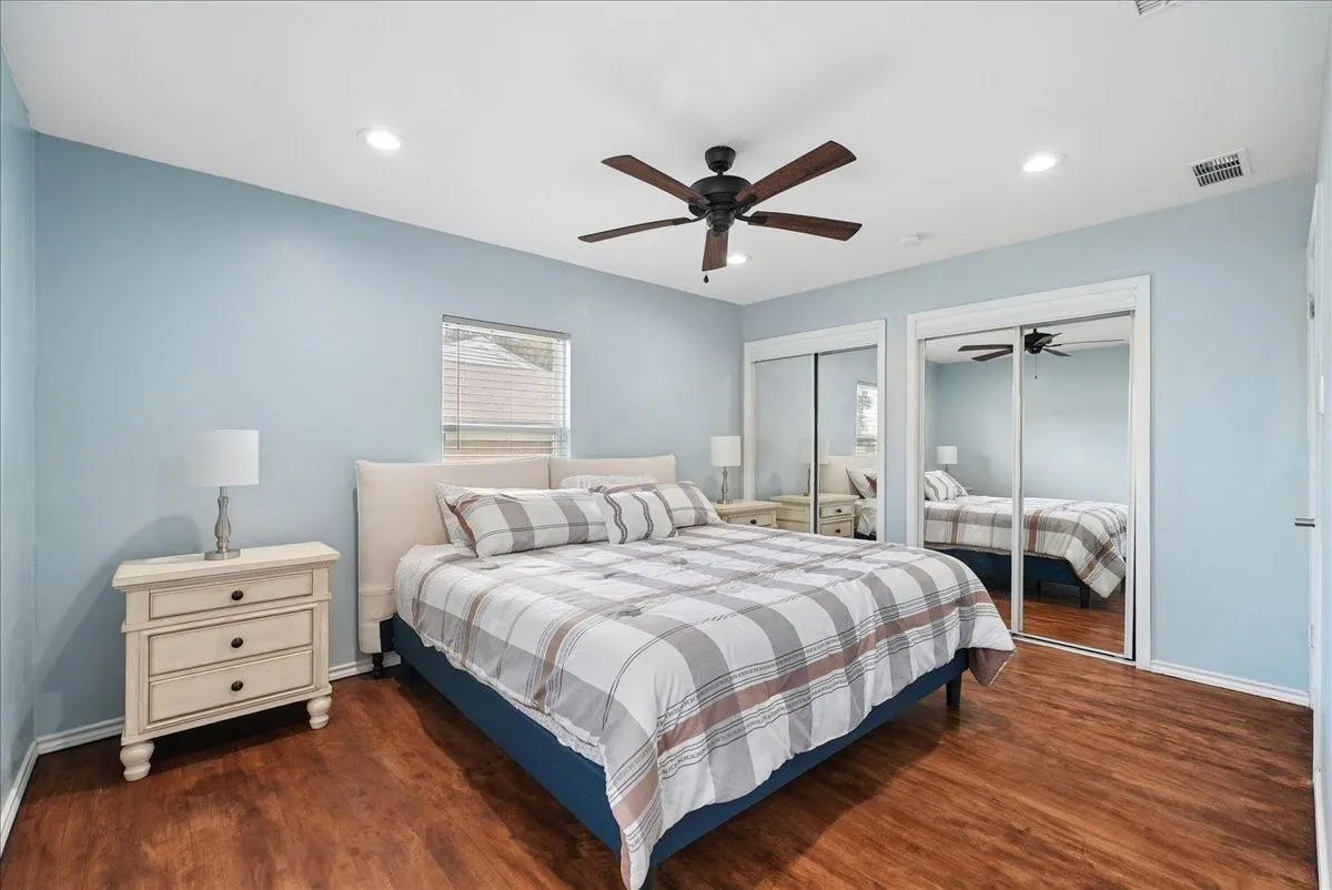 Wood-finish flooring, recessed lighting, ceiling fan, and sliding mirrored closet doors