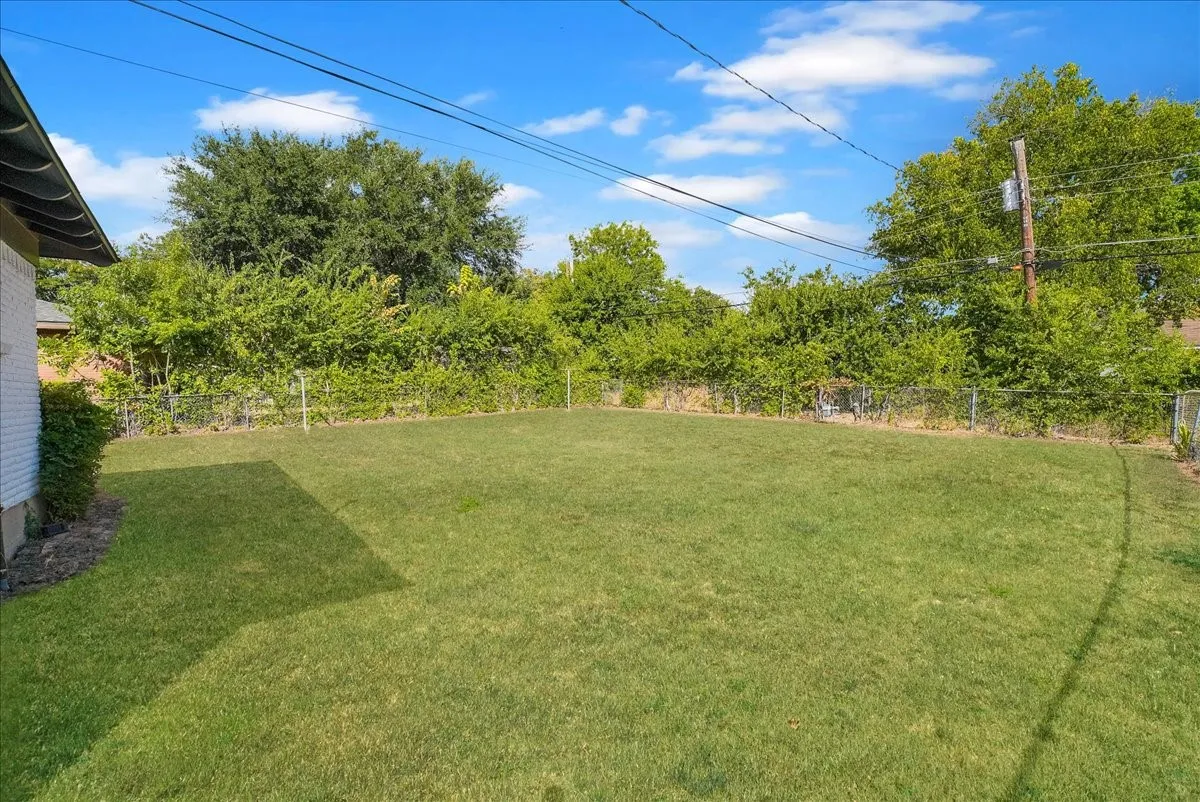 Expansive lawn area enclosed by chain-link fencing and mature perimeter greenery