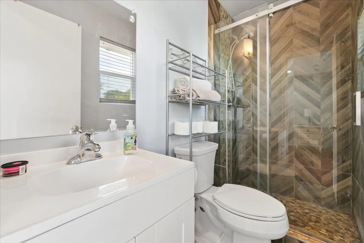 Sliding glass shower enclosure with herringbone-patterned tile walls and stone flooring