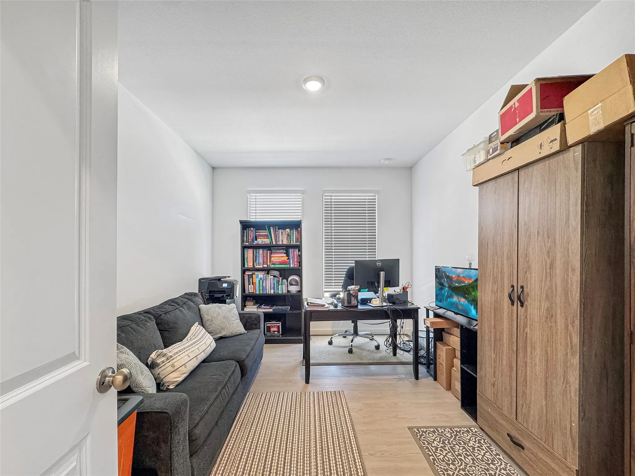 Recessed ceiling lighting, wood-finish flooring, and multiple windows with blinds