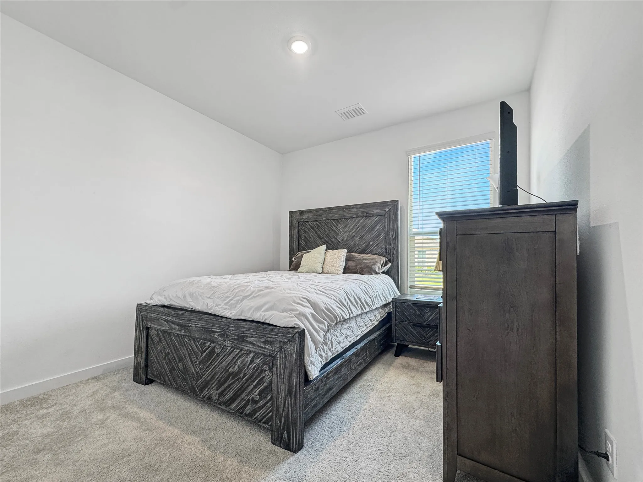 Recessed ceiling lighting, light gray wall paint, window with blinds, light gray carpet flooring, white trim