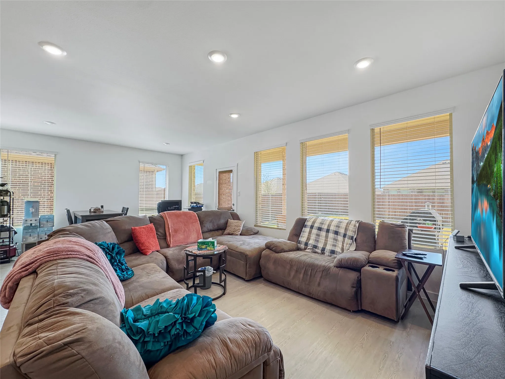 Recessed lighting, light wood-finish flooring, multiple windows with blinds, and an open-concept layout