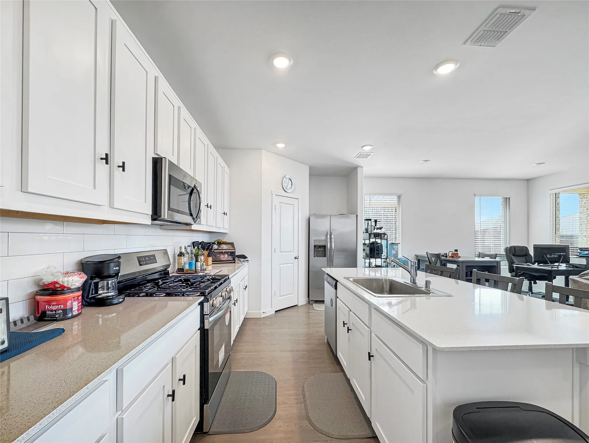 Kitchen featuring white cabinetry, light-toned countertops, stainless steel appliances, and wood-finish flooring
