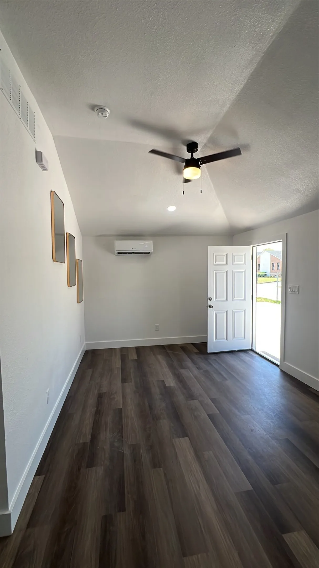 Vaulted ceiling with an integrated ceiling fan, wood-finish flooring, and white interior walls