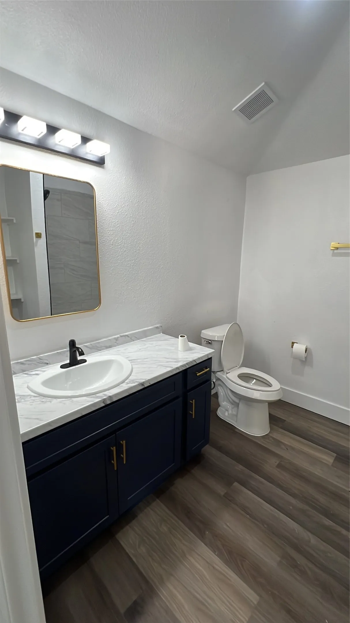 Navy blue vanity with gold-finish hardware, white oval sink, and a white countertop