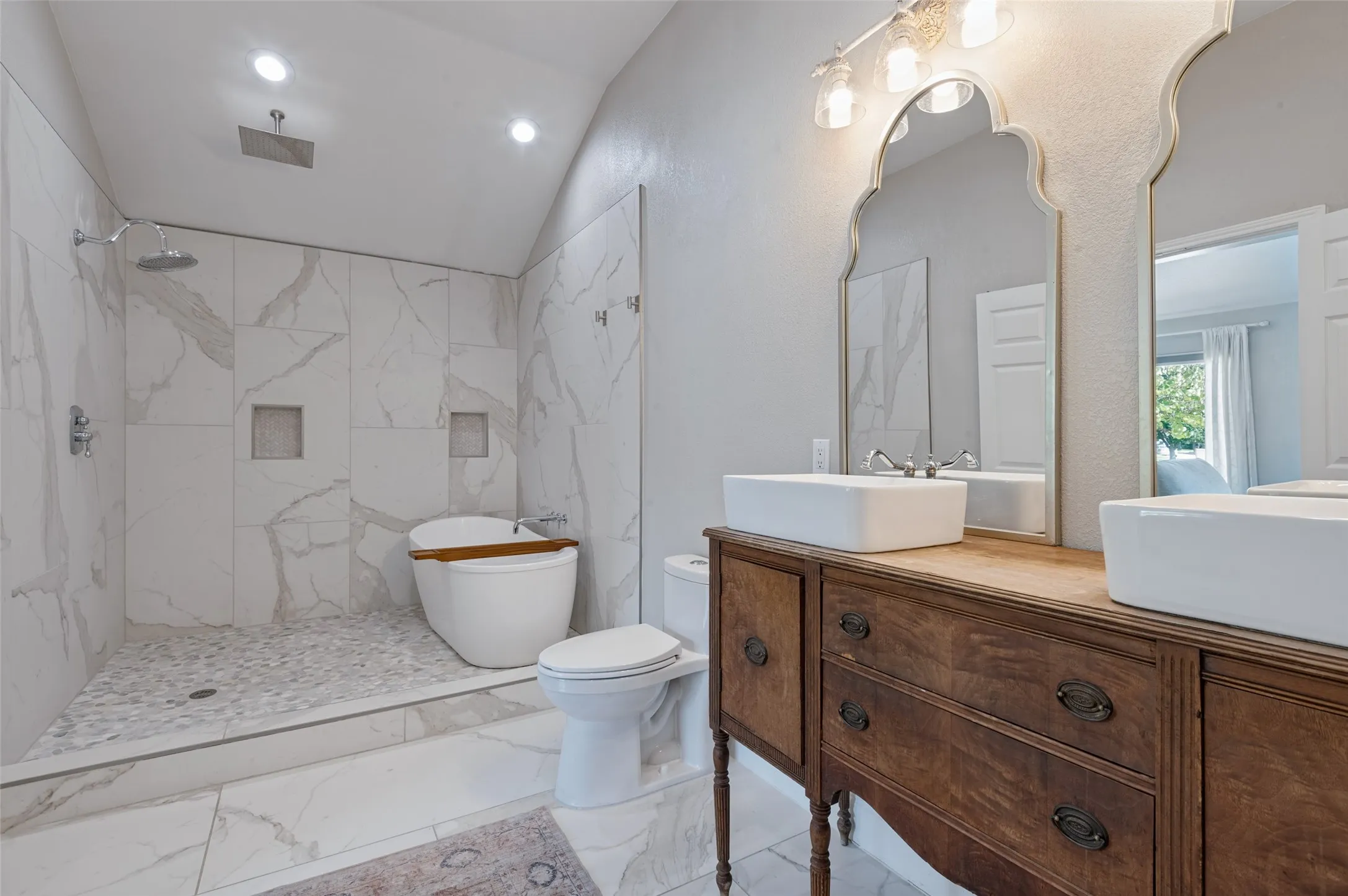 Primary bath includes a soaking tub, walk-in shower with stone pebble flooring, rainfall showerhead and dual vessel sinks