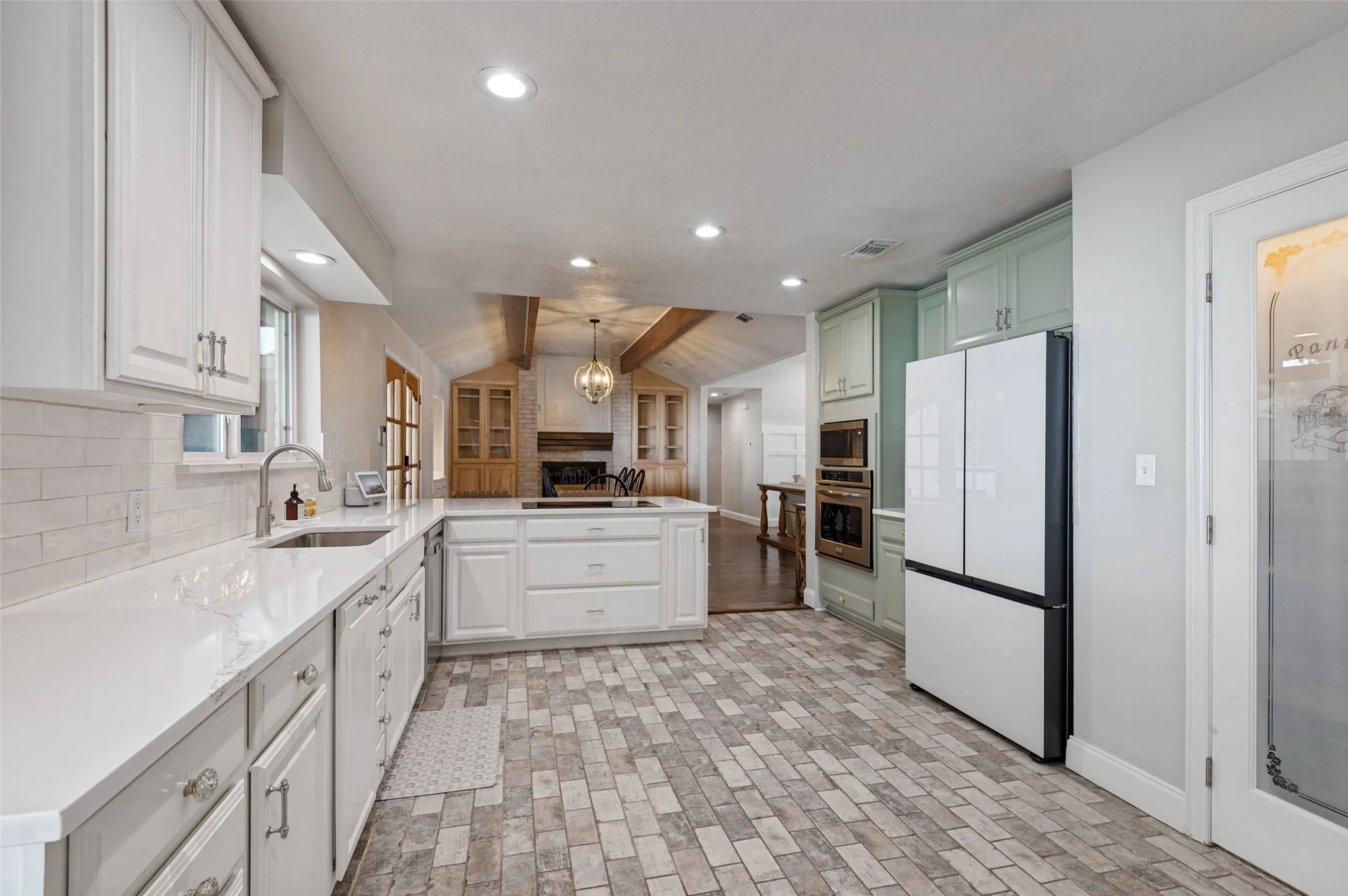 Kitchen featuring white cabinetry, white quartz countertops, white subway tile backsplash, custom cabinetry, pantry