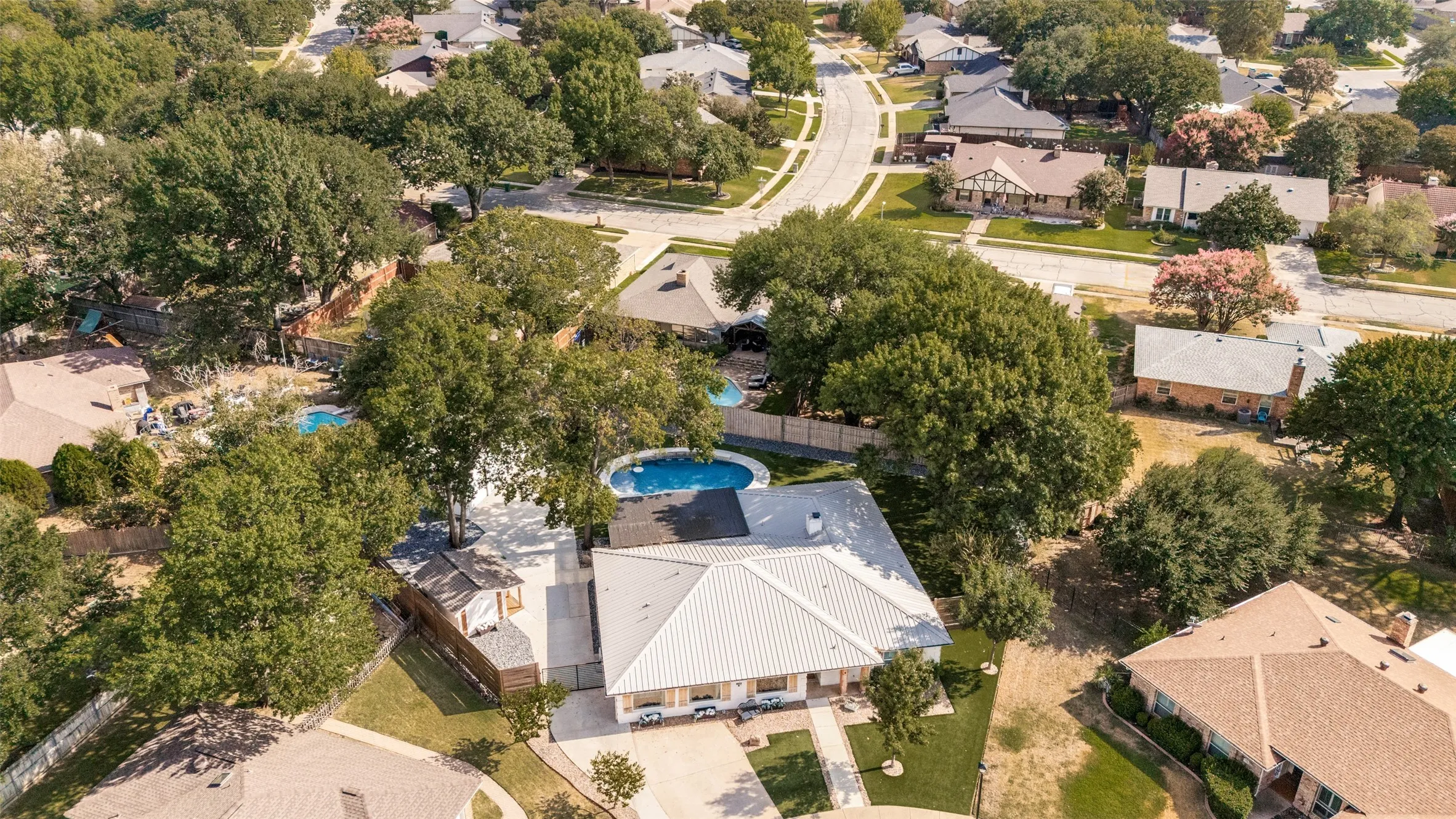 Residence featuring a light-colored metal roof, separate flex room and an inground swimming pool