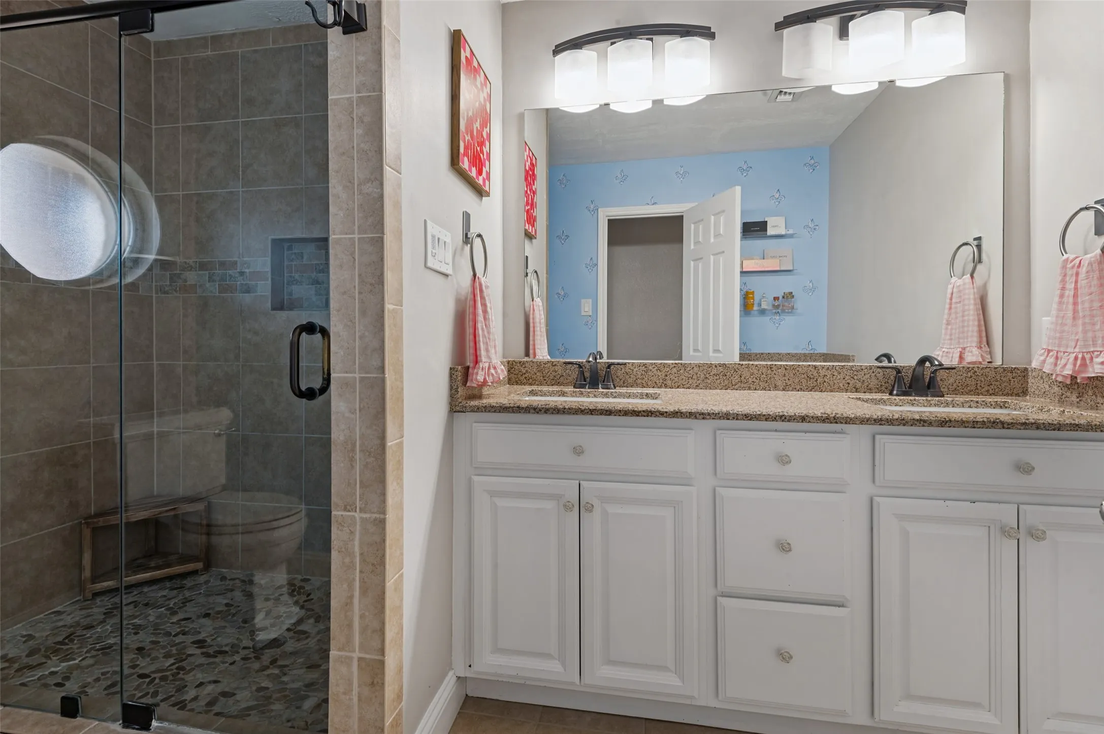 Large shower, dual vanity, granite countertop, white cabinetry in bathroom