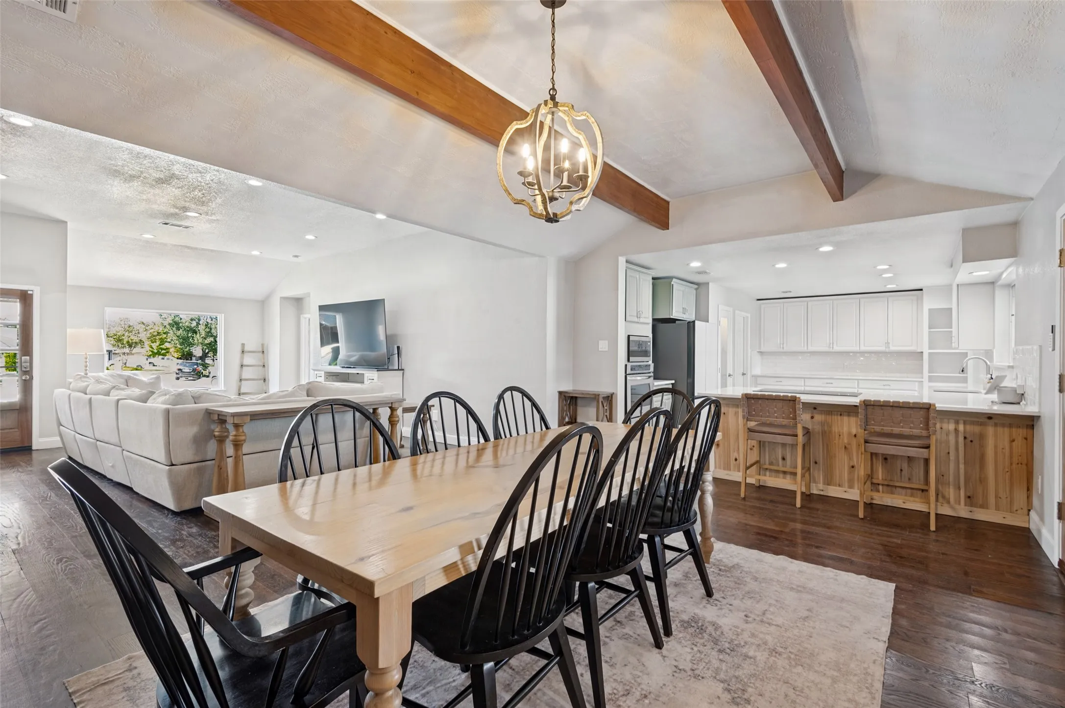 Vaulted ceiling with exposed wood beams in dining room, wood flooring, chandelier